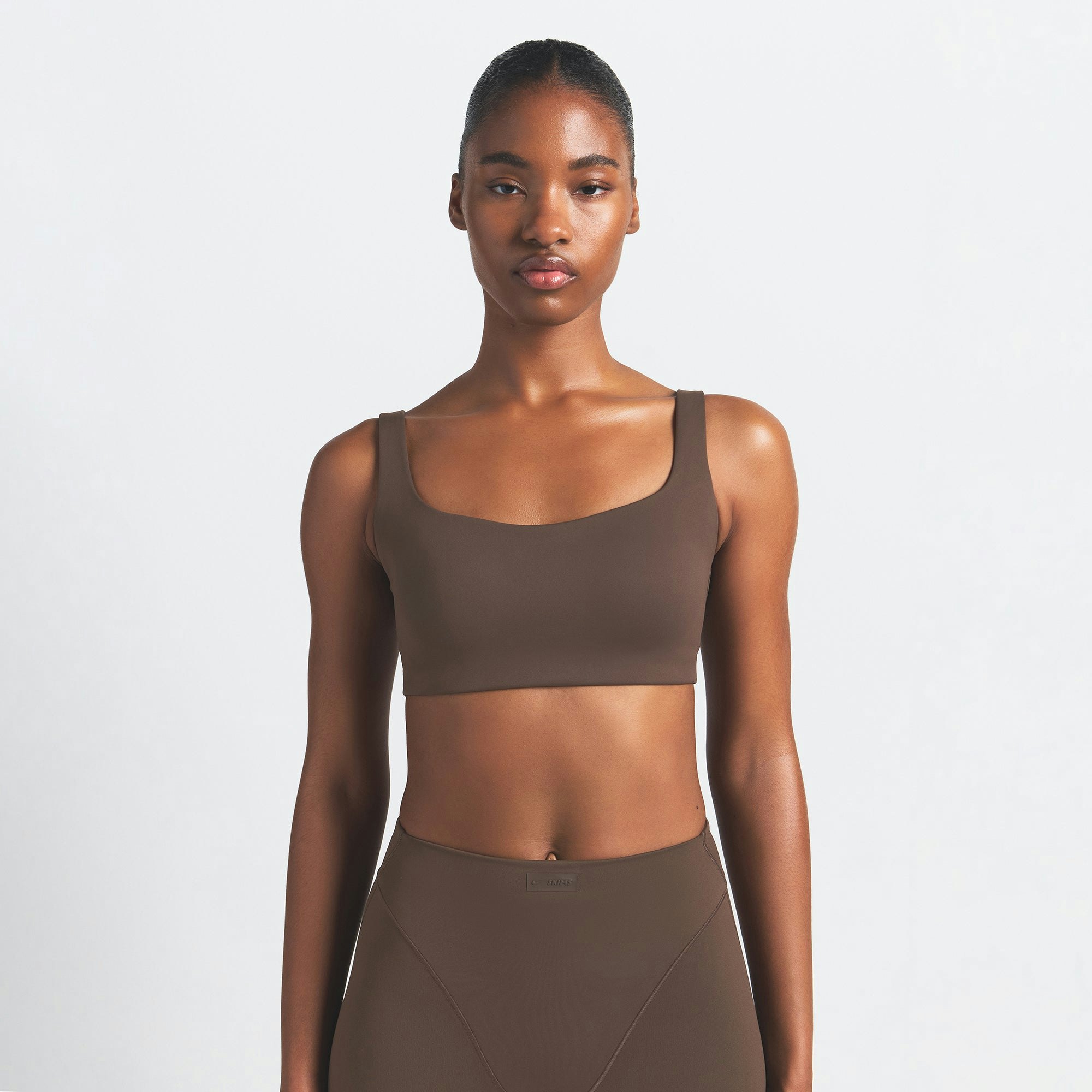 NikeSKIMS MATTE SCOOP NECK BRA | DARK SEPIA ON A MODEL FRONT VIEW