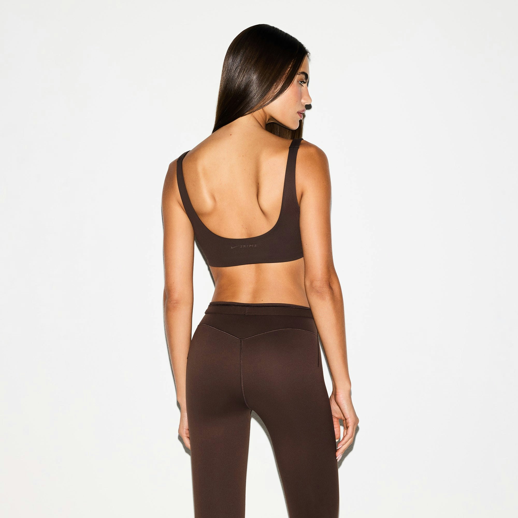 NikeSKIMS MATTE SCOOP NECK BRA | DARK SEPIA ON A MODEL BACK VIEW @ | FOCUS: 0.0, 1.0, 0.9