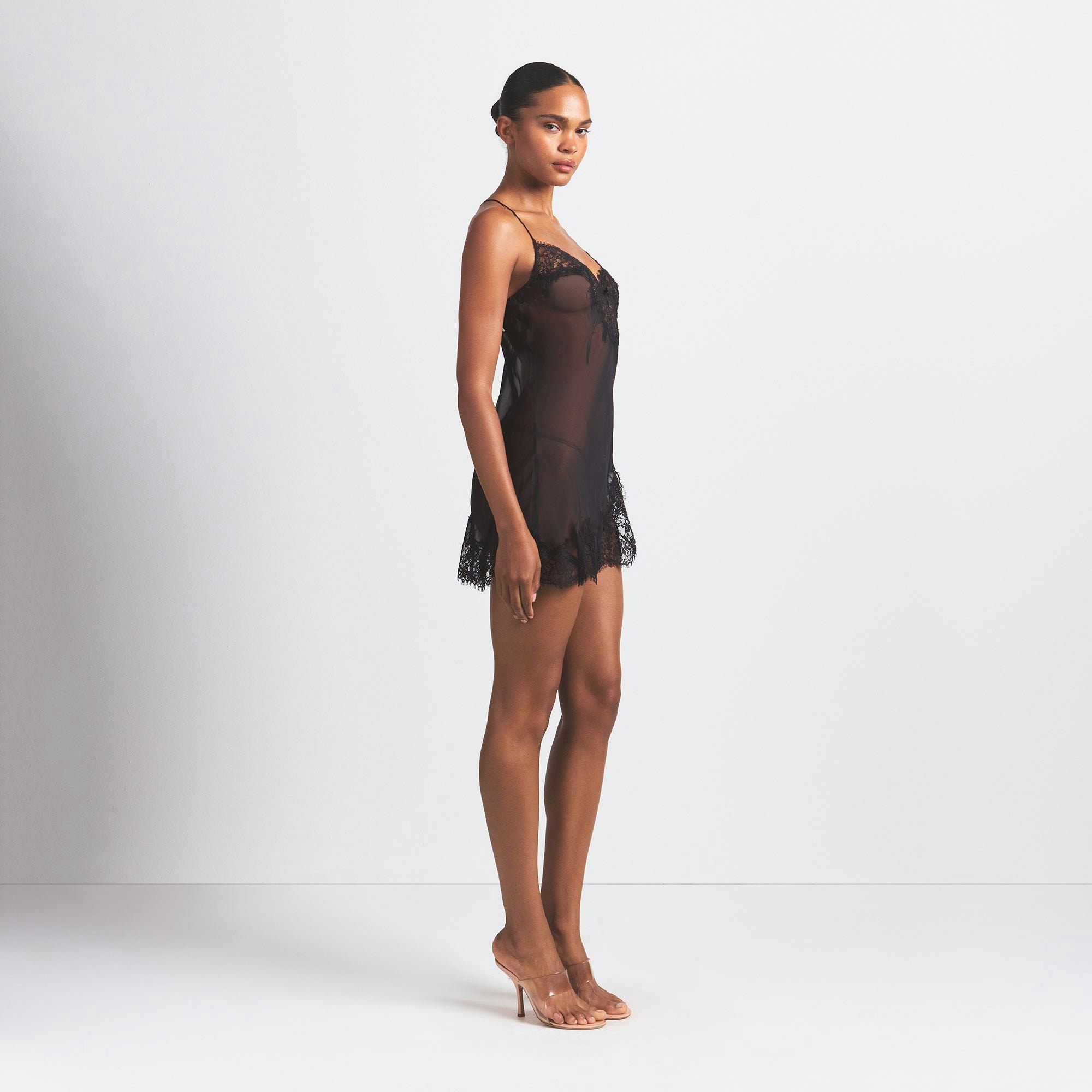 SKIMS ROMANCE LACE MINI SLIP DRESS | ONYX ON A MODEL SIDE VIEW @ | FOCUS: 0.0, 1.0, 0.9