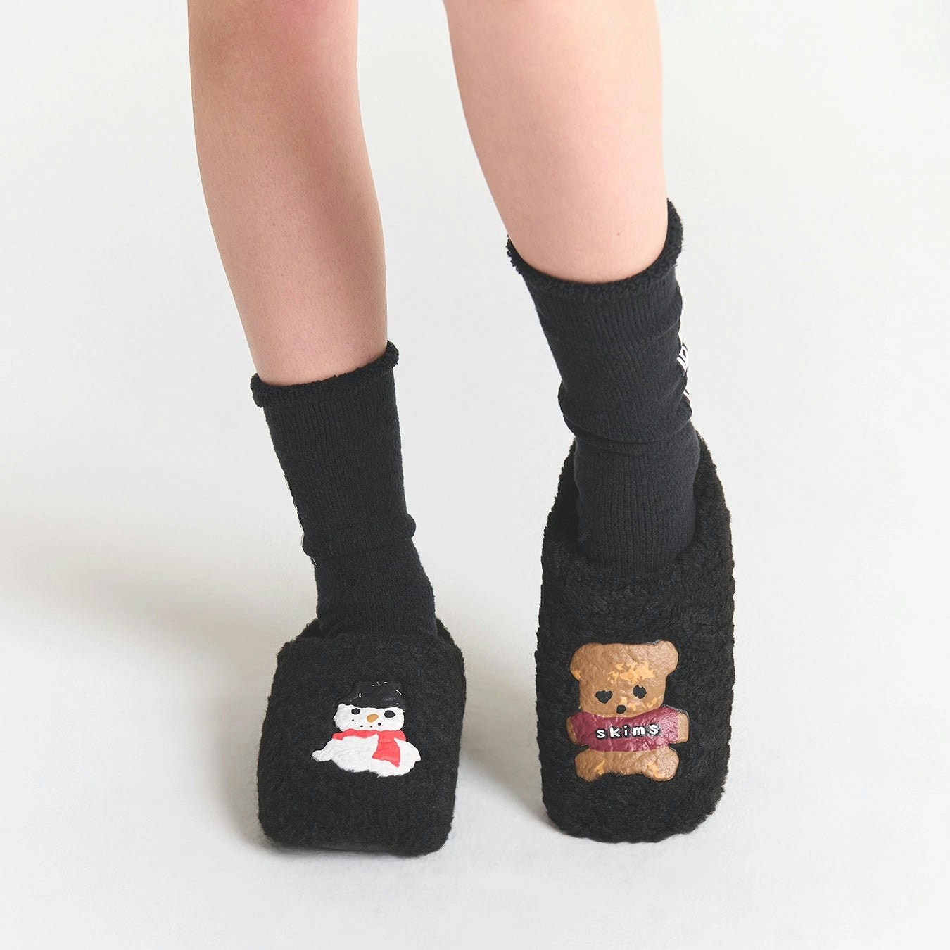 CACTUS PLANT FLEA MARKET X SKIMS SHERPA SLIPPER | ONYX GINGERBREAD SNOWMAN PRINT ON A MODEL SIDE VIEW FOCUS: 0.0, 1.0, 0.9