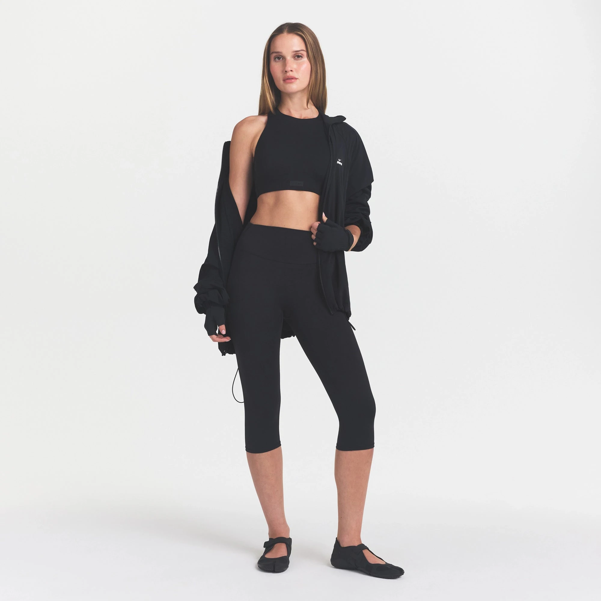 NikeSKIMS MATTE CROP 17" LEGGING | OBSIDIAN ON A MODEL BACK VIEW @ | FOCUS: 0.0, 1.0, 0.9