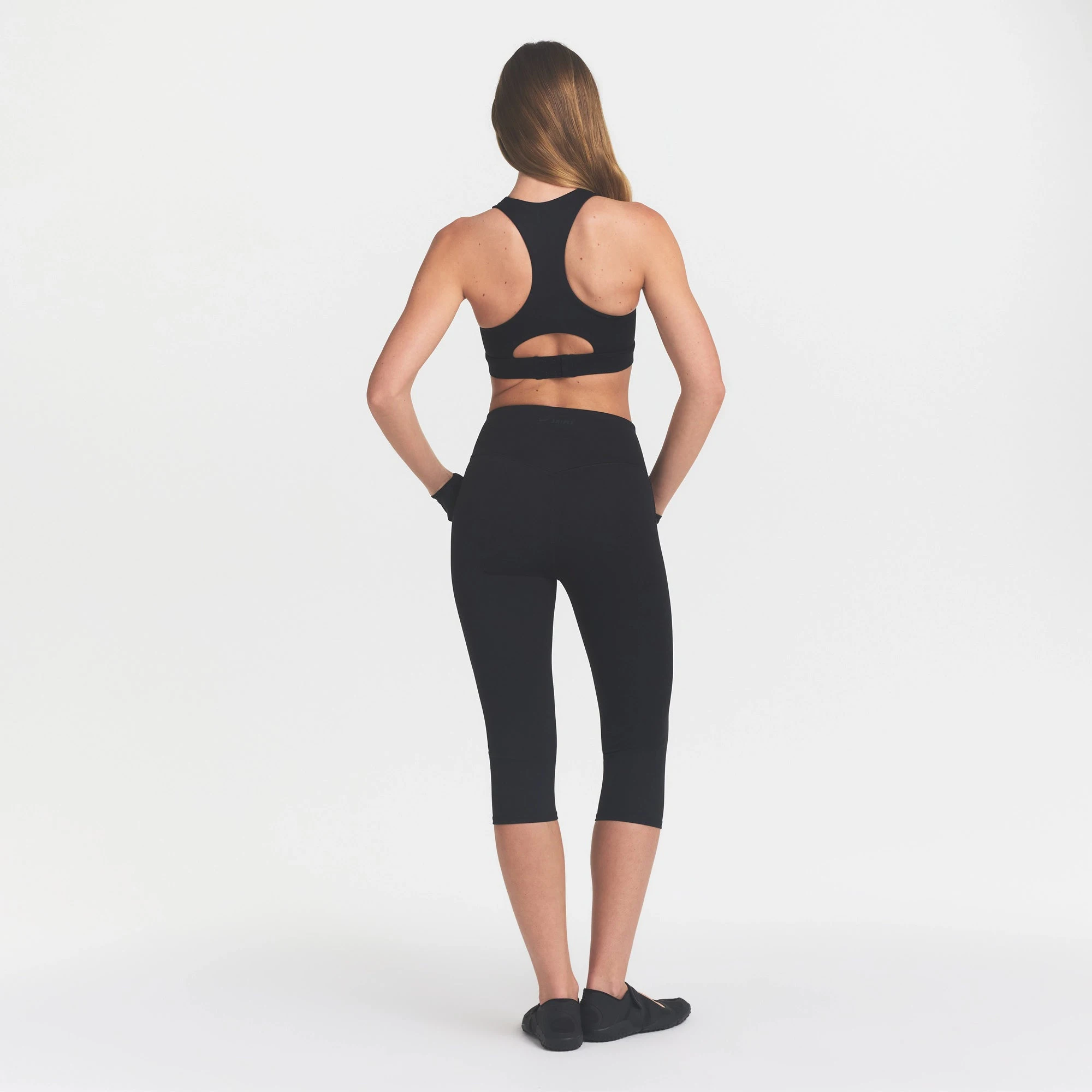 NikeSKIMS MATTE CROP 17" LEGGING | OBSIDIAN ON A MODEL BACK VIEW @ | FOCUS: 0.0, 1.0, 0.9