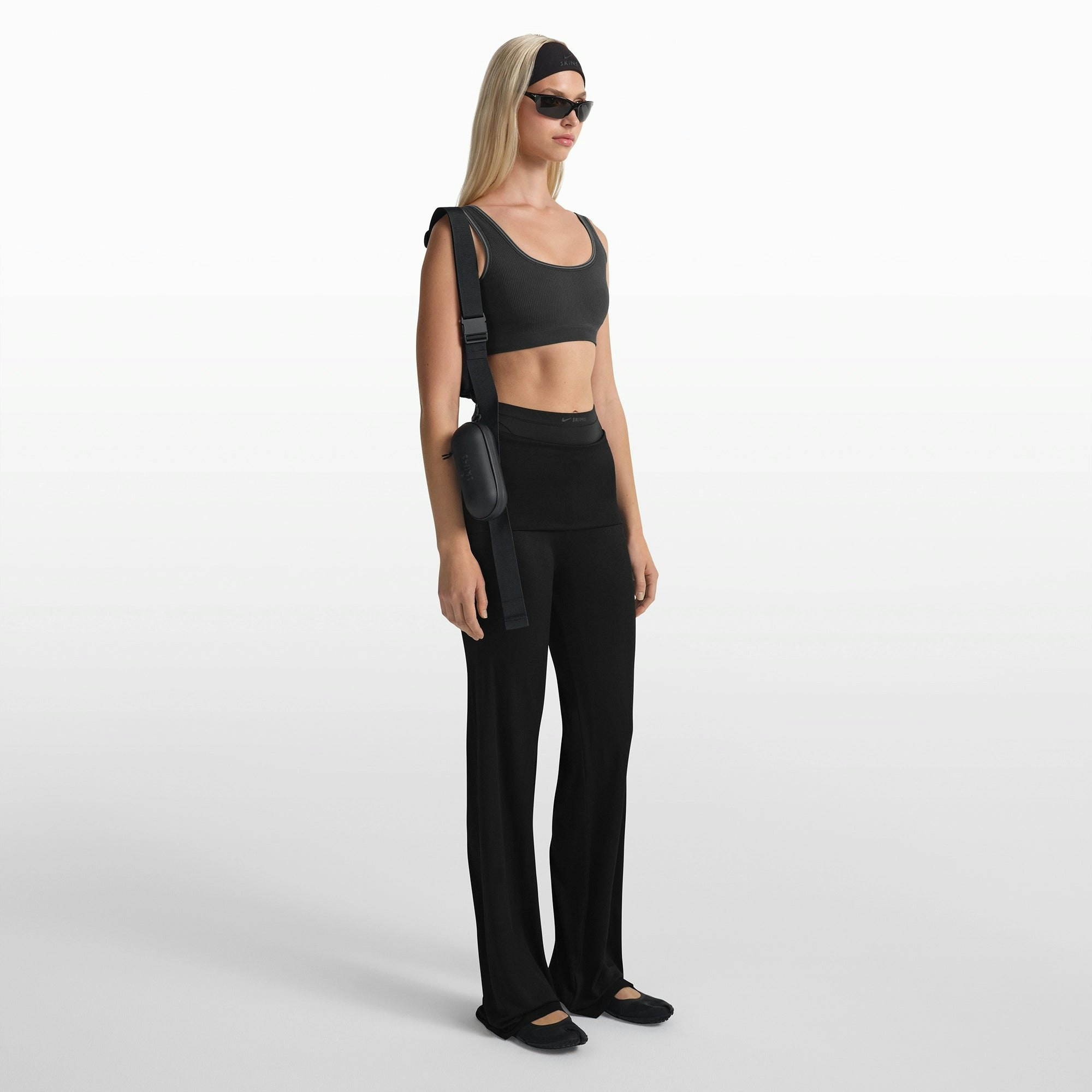 NikeSKIMS ACCESSORIES HARDSHELL GLASSES CASE | OBSIDIAN ON A MODEL FRONT VIEW @ | FOCUS: 0.0, 1.0, 0.9