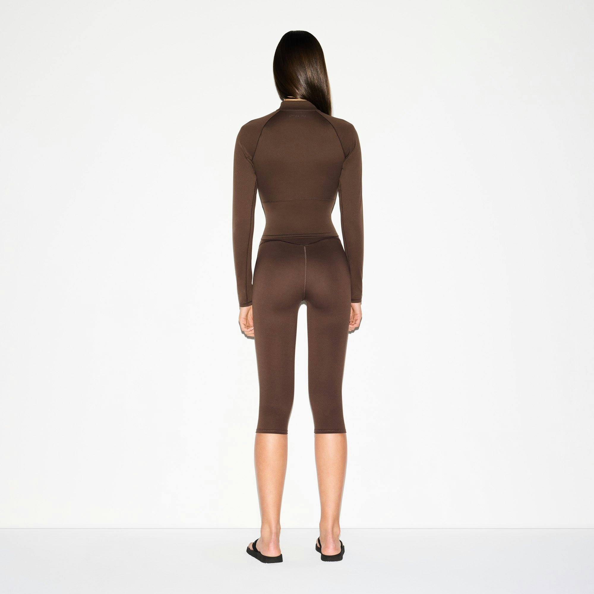 NikeSKIMS MATTE CROP 17" LEGGING | DARK SEPIA ON A MODEL BACK VIEW @ | FOCUS: 0.0, 1.0, 0.9