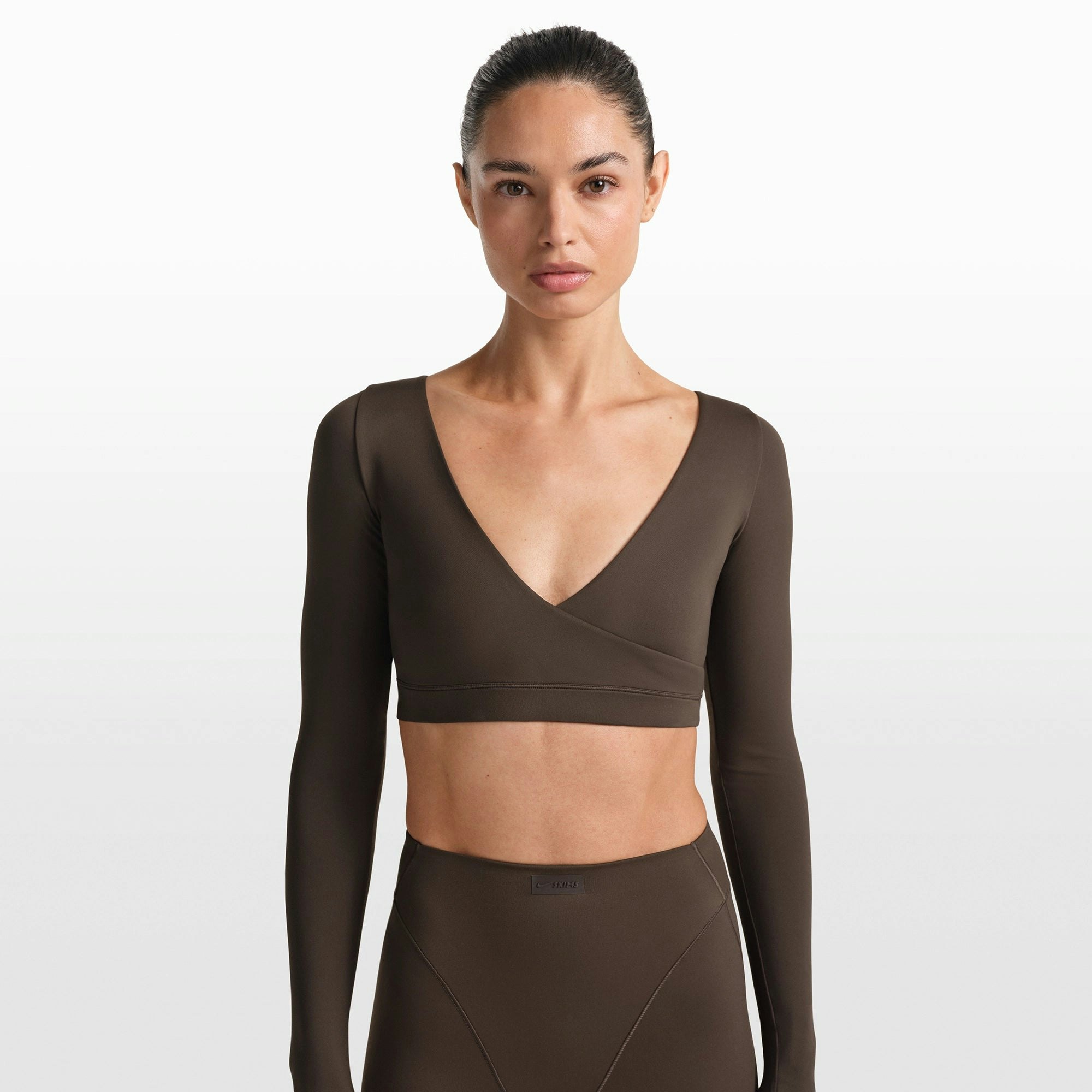 NikeSKIMS MATTE WRAP LONG SLEEVE CROPPED TOP | DARK SEPIA ON A MODEL FRONT VIEW @ | FOCUS: 0.0, 1.0, 0.9