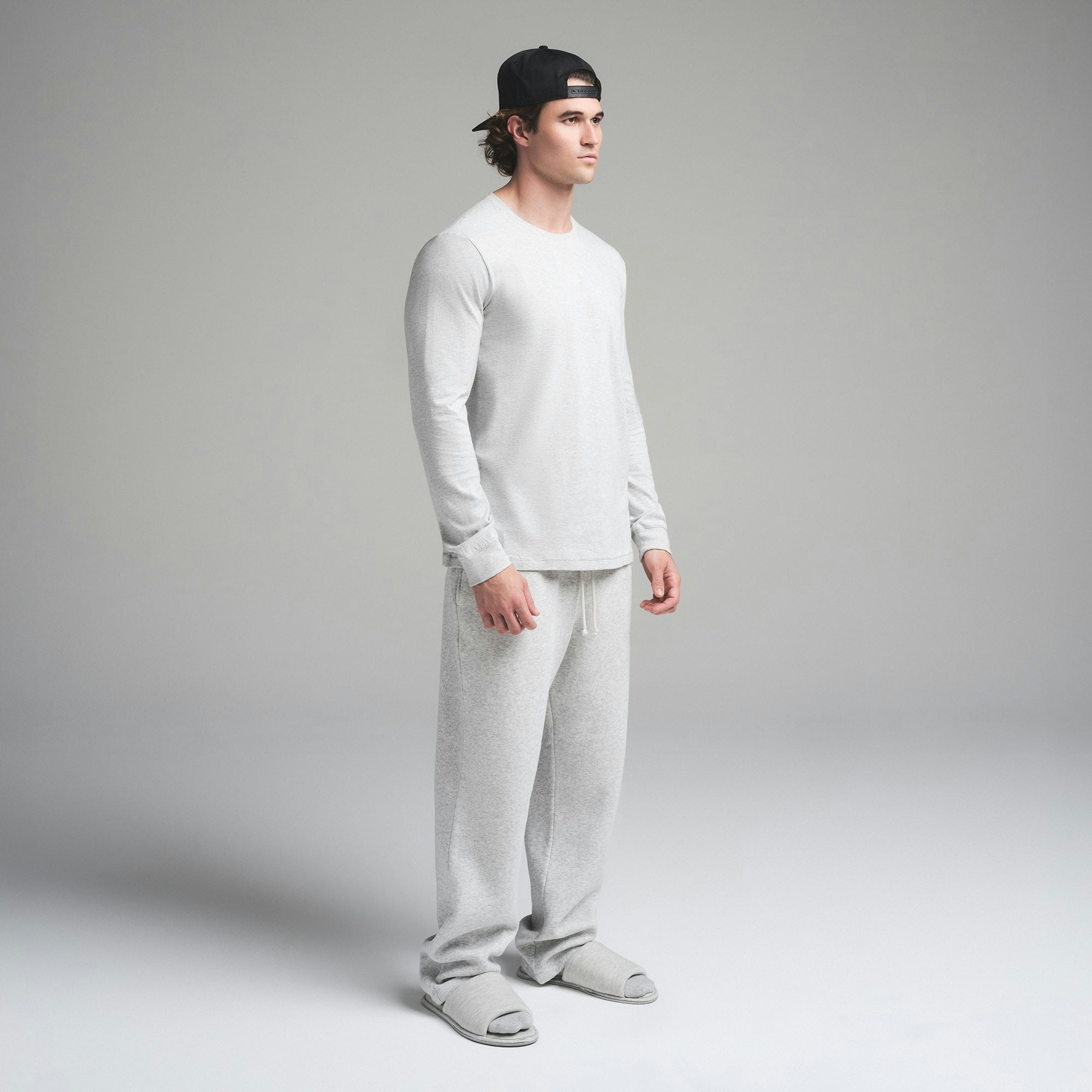 SKIMS COTTON MENS CLASSIC LONG SLEEVE T-SHIRT | LIGHT HEATHER GREY ON A MODEL SIDE VIEW | FOCUS: 0.0, 1.0, 0.9