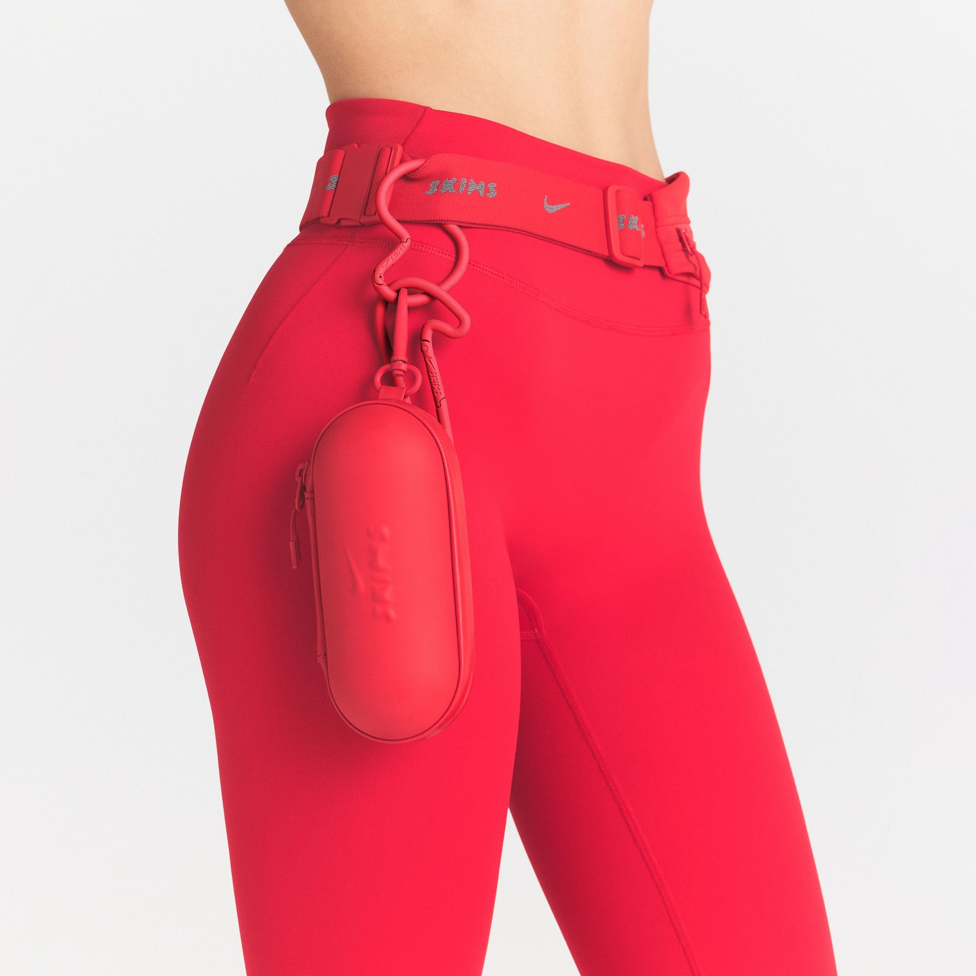 NikeSKIMS ACCESSORIES HARDSHELL GLASSES CASE | UNIVERSITY RED ON A MODEL SIDE VIEW @ | FOCUS: 0.0, 1.0, 0.9