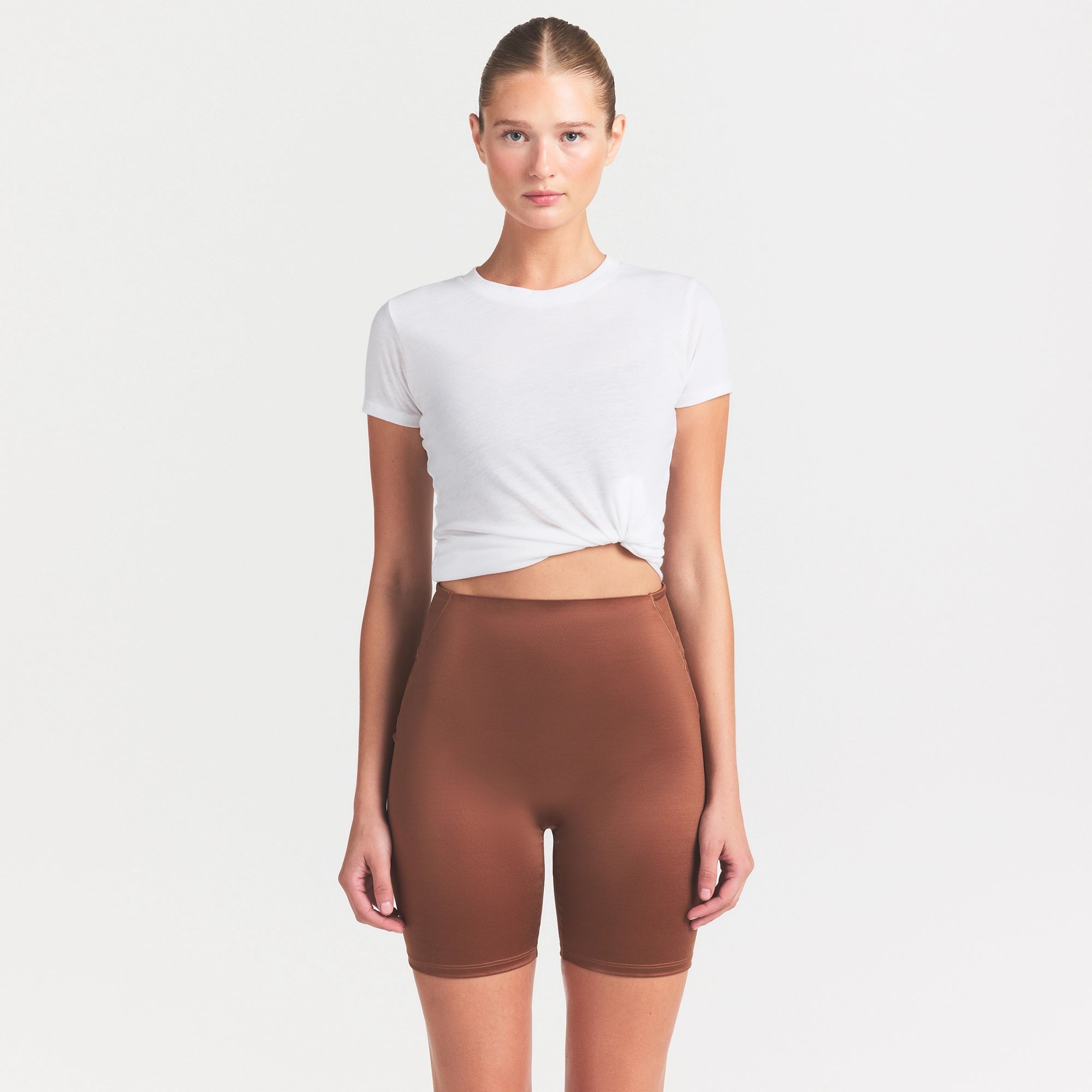 NikeSKIMS SATIN SHINE BONDED WAIST 7" BIKER SHORT | CAROB BROWN ON A MODEL SIDE VIEW @ | FOCUS: 0.0, 1.0, 0.9