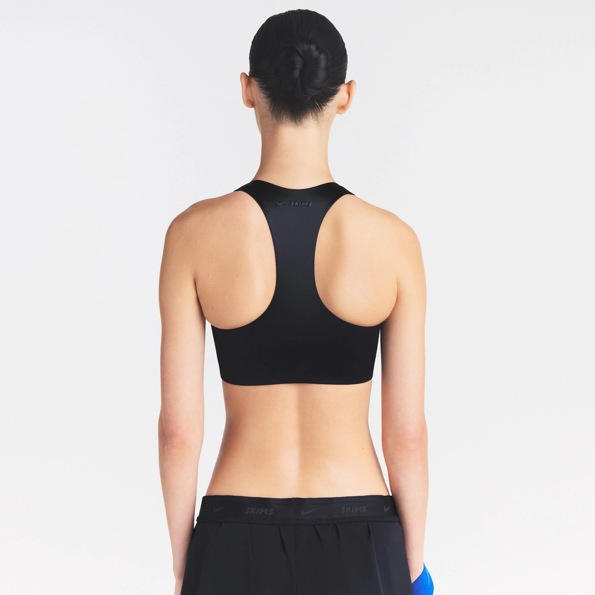 NikeSKIMS SATIN SHINE RACER BACK ZIP FRONT BRA | OBSIDIAN ON A MODEL SIDE VIEW @ | FOCUS: 0.0, 1.0, 0.9