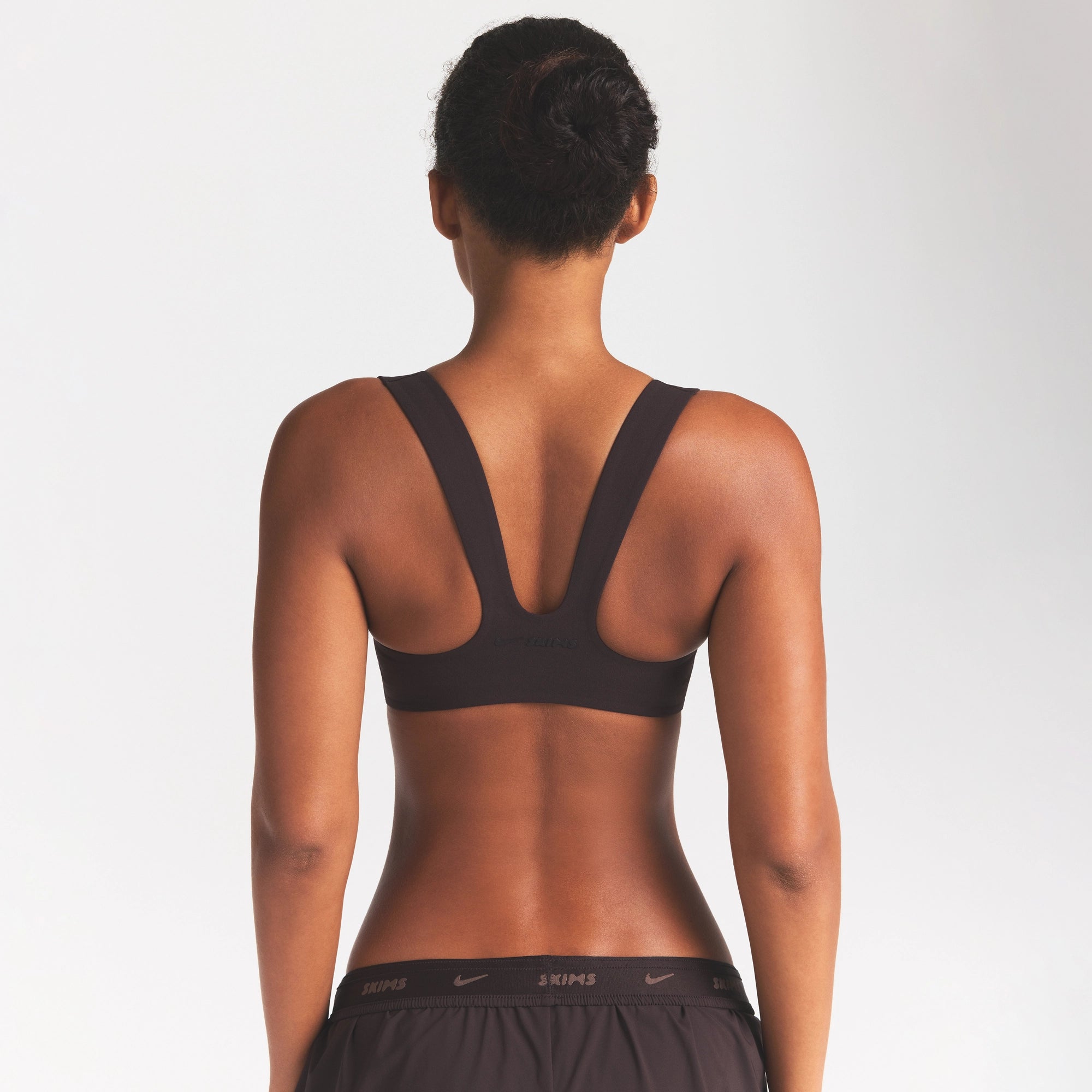 NikeSKIMS STUDIO STRETCH RACERBACK BRA | DARK ROAST ON A MODEL SIDE VIEW