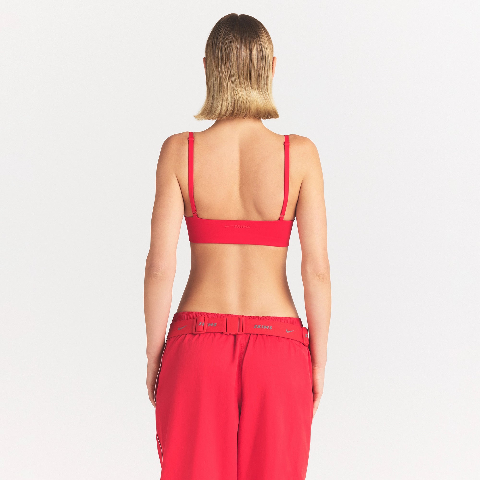 NikeSKIMS MATTE MICRO SCOOP BRA | UNIVERSITY RED ON A MODEL SIDE VIEW @ | FOCUS: 0.0, 1.0, 0.9