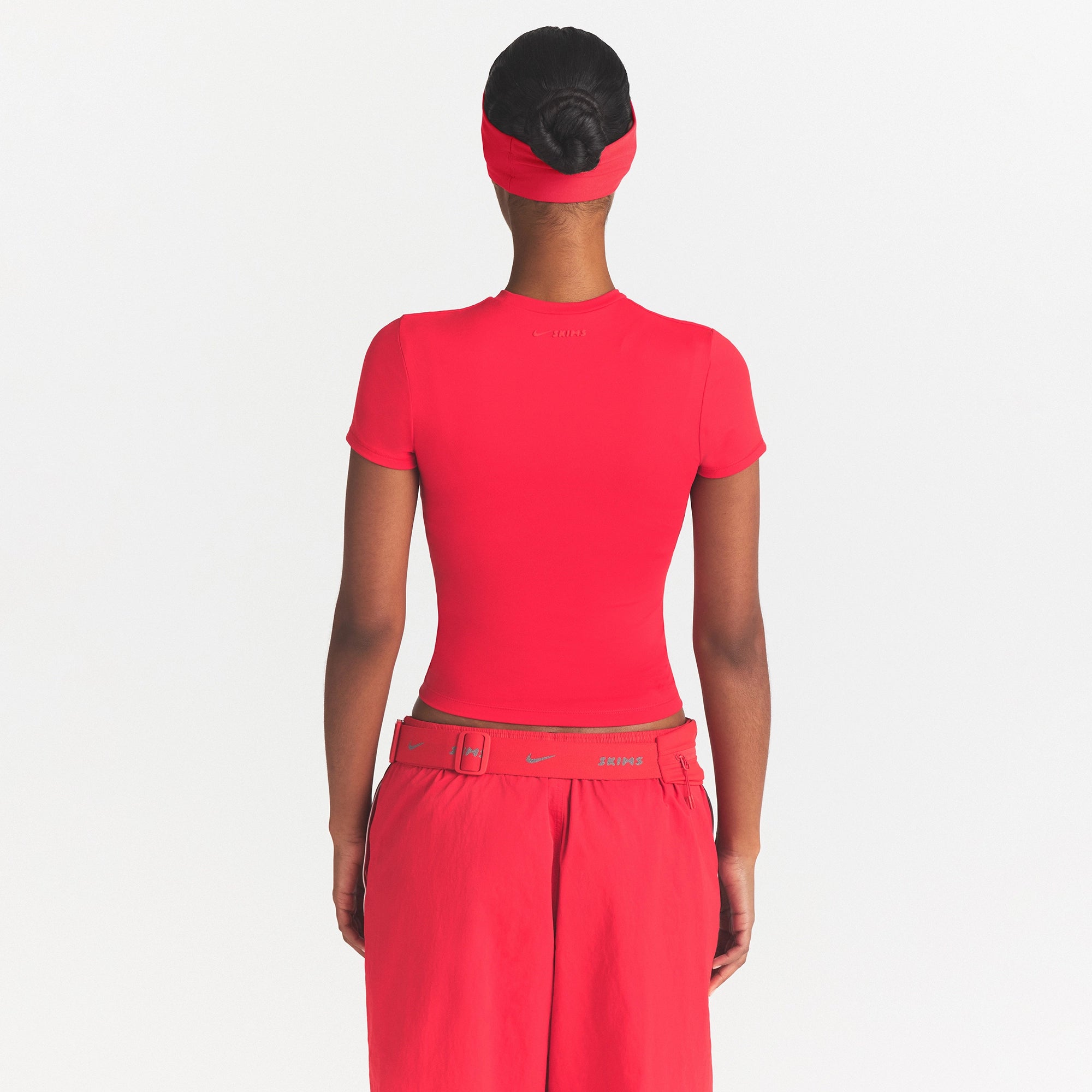 NikeSKIMS MATTE PADDED BABY TEE | UNIVERSITY RED ON A MODEL SIDE VIEW @ | FOCUS: 0.0, 1.0, 0.9