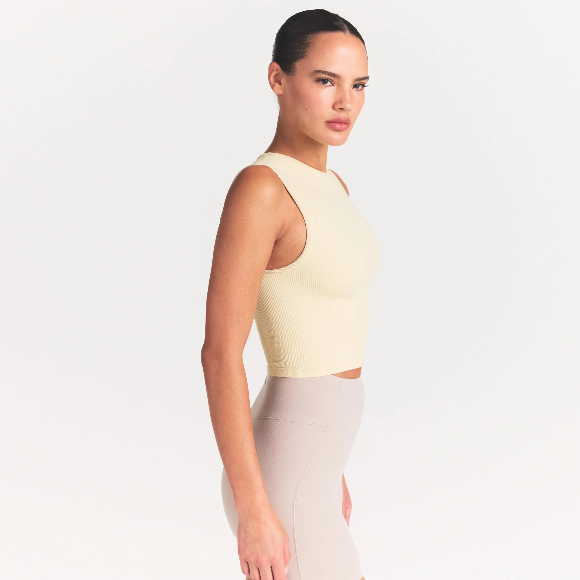 NikeSKIMS RIBBED SEAMLESS MUSCLE TANK | LEMON DROP ON A MODEL SIDE VIEW @ | FOCUS: 0.0, 1.0, 0.9