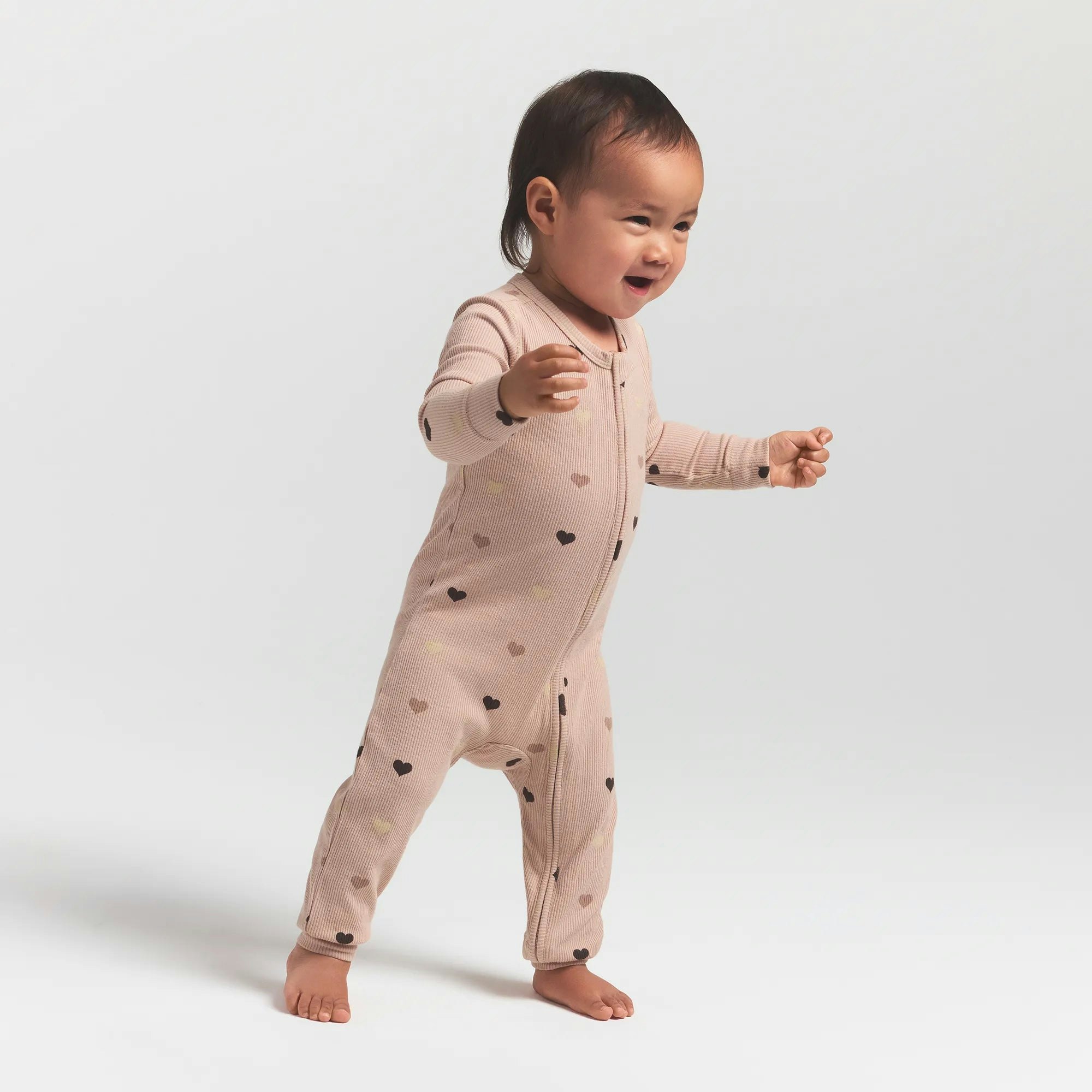 SOFT LOUNGE BABY ONESIE | MICA MINI HEART HALFDROP ON A MODEL SIDE VIEW @ | FOCUS: 0.0, 1.0, 0.9