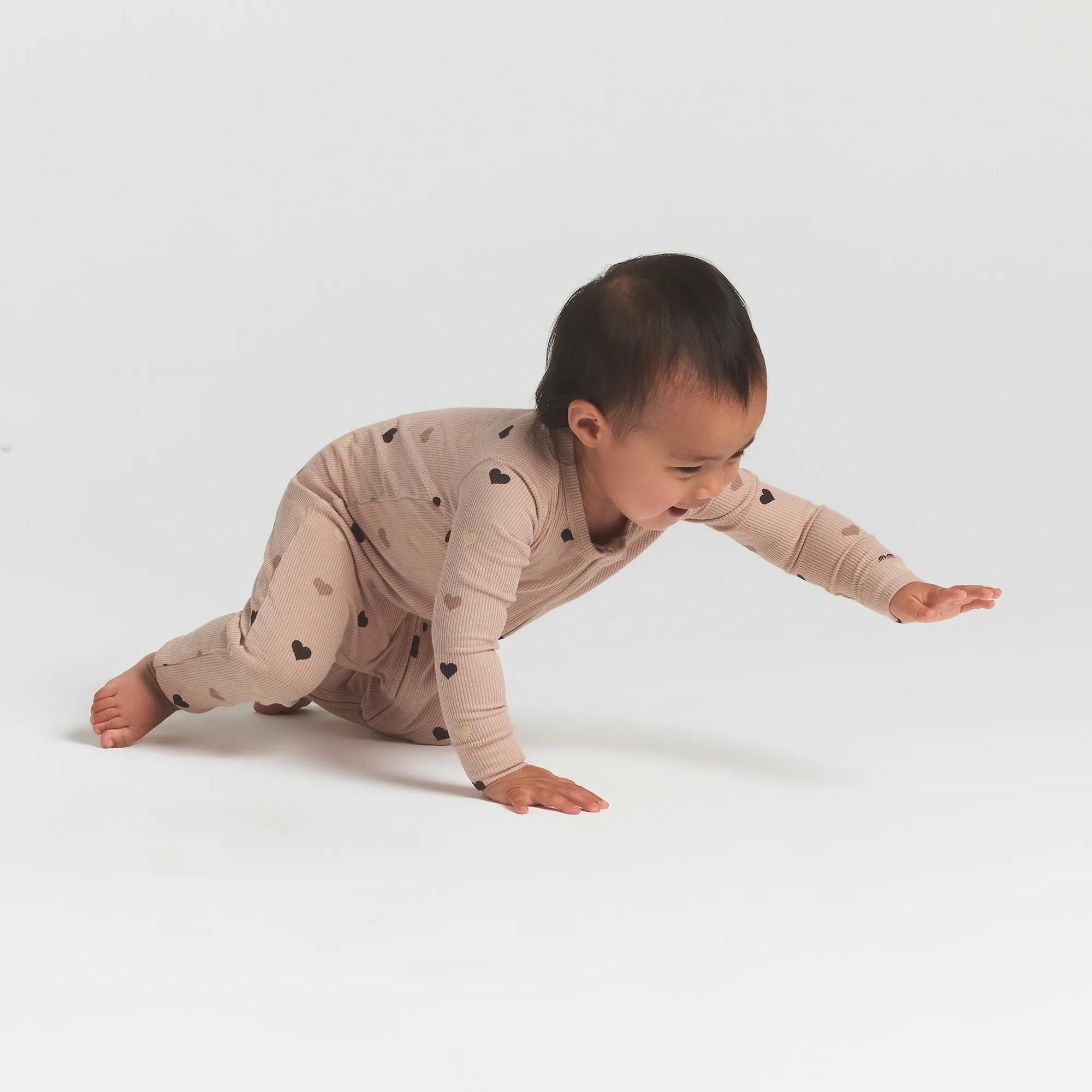 SOFT LOUNGE BABY ONESIE | MICA MINI HEART HALFDROP ON A MODEL SIDE VIEW @ | FOCUS: 0.0, 1.0, 0.9
