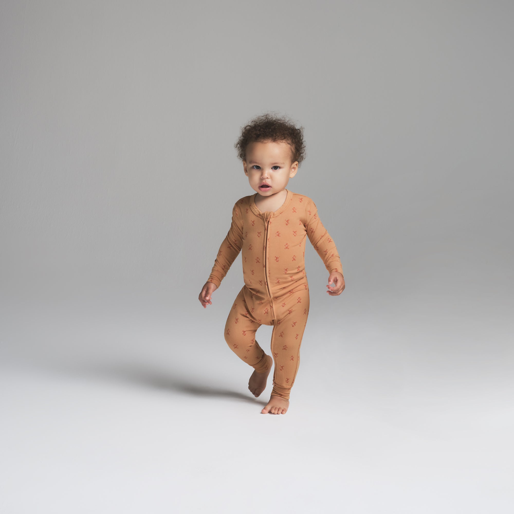 SKIMS SLEEP BABY ONESIE | CARAMEL GINGERBREAD PRINT ON A MODEL FRONT VIEW | FOCUS: 0.0, 1.0, 0.9