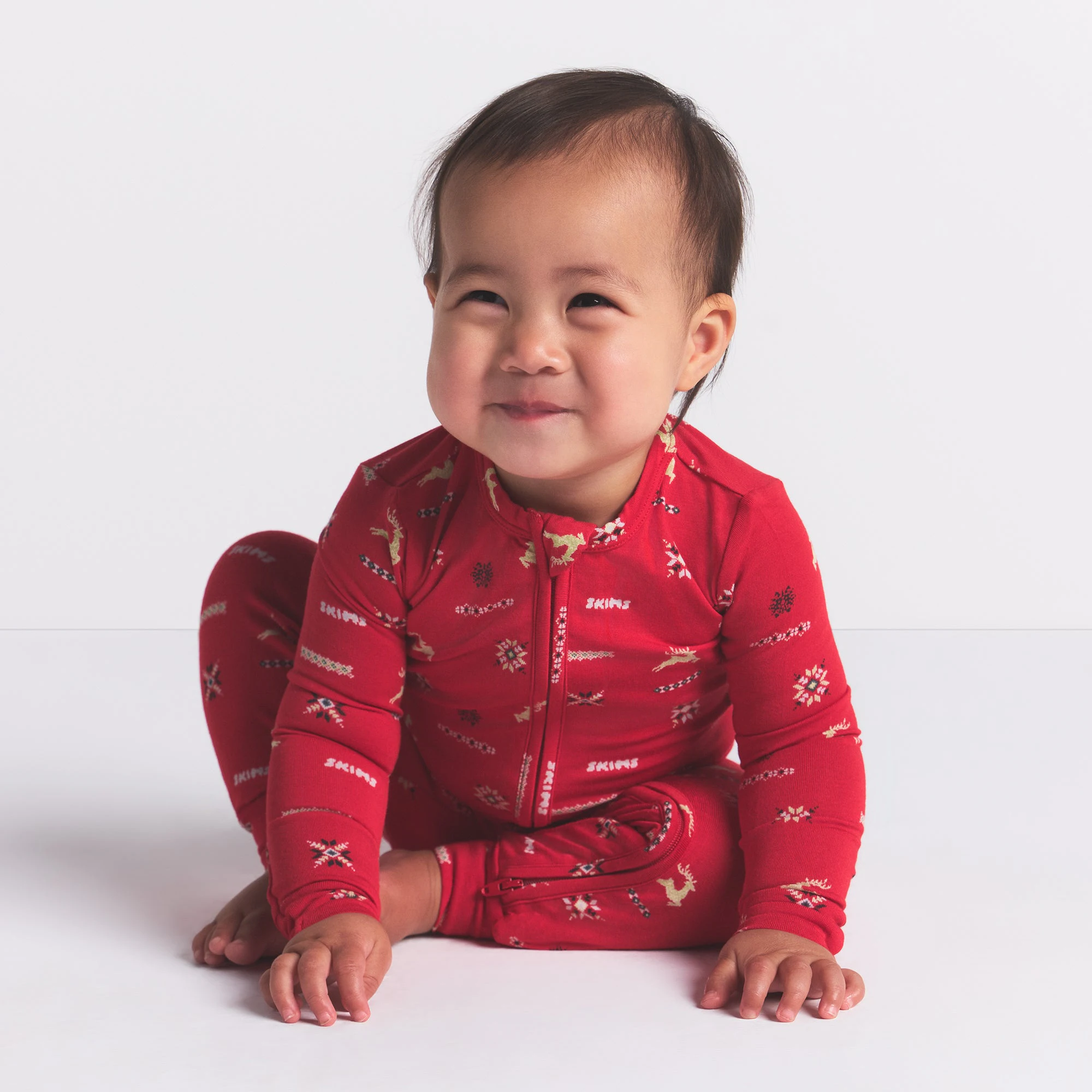 SKIMS SLEEP BABY ONESIE | CRANBERRY VINTAGE DEER PRINT ON A MODEL FRONT VIEW @ | FOCUS: 0.0, 1.0, 0.9