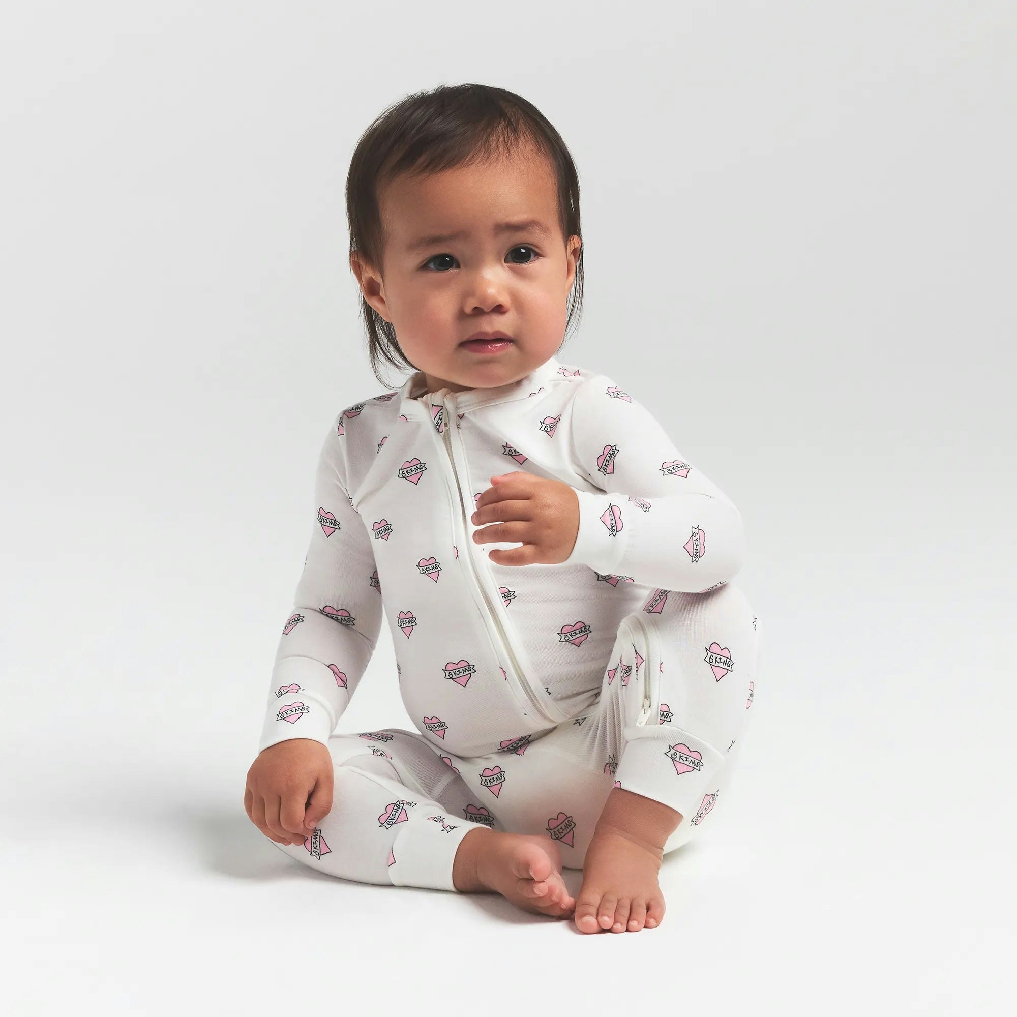 SKIMS SLEEP BABY ONESIE | MARBLE HEART BANNER ON A MODEL FRONT VIEW @ | FOCUS: 0.0, 1.0, 0.9