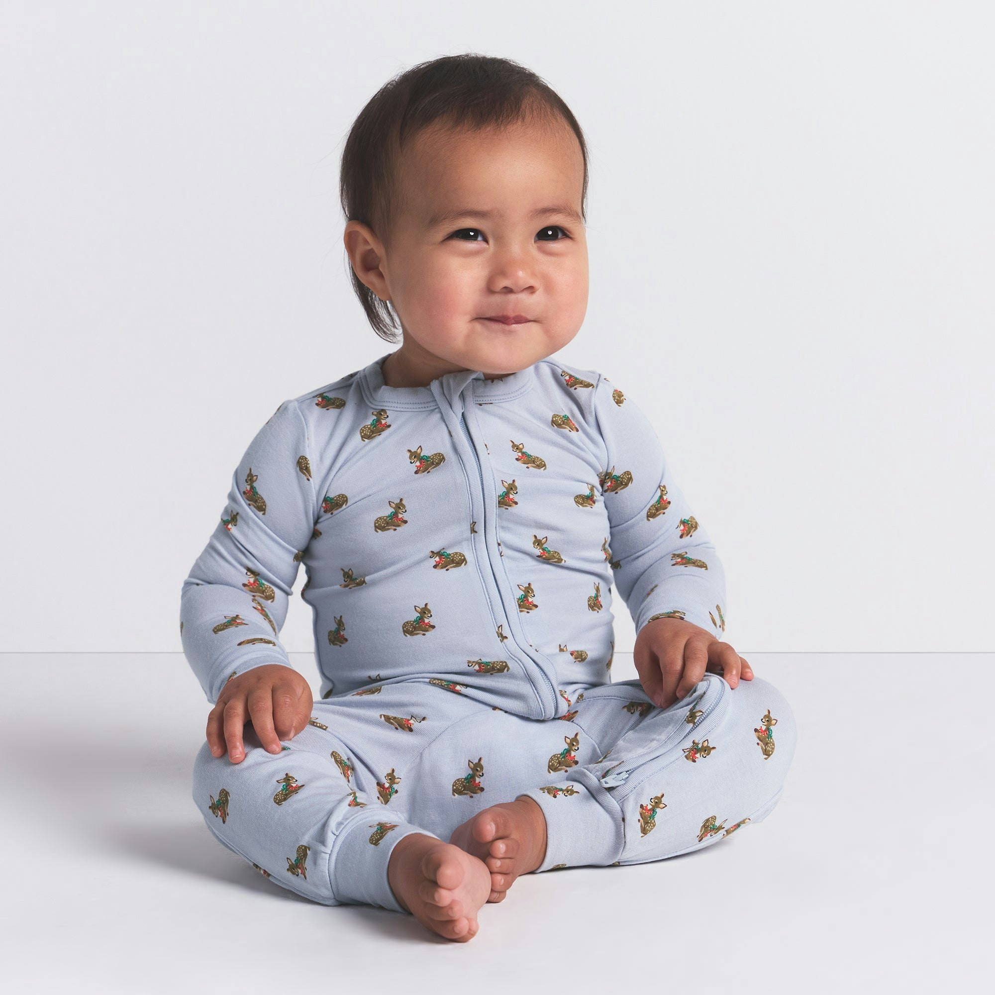 SKIMS SLEEP BABY ONESIE | ZEN BLUE BABY DEER PRINT ON A MODEL FRONT VIEW @ | FOCUS: 0.0, 1.0, 0.9