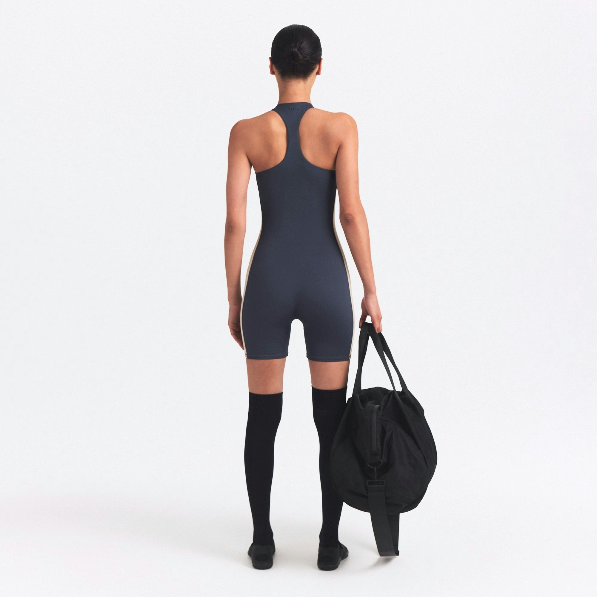 NikeSKIMS MATTE AND SHINE RACERBACK 5" ONE PIECE | DEEP ROYAL/STONE ON A MODEL SIDE VIEW @ | FOCUS: 0.0, 1.0, 0.9