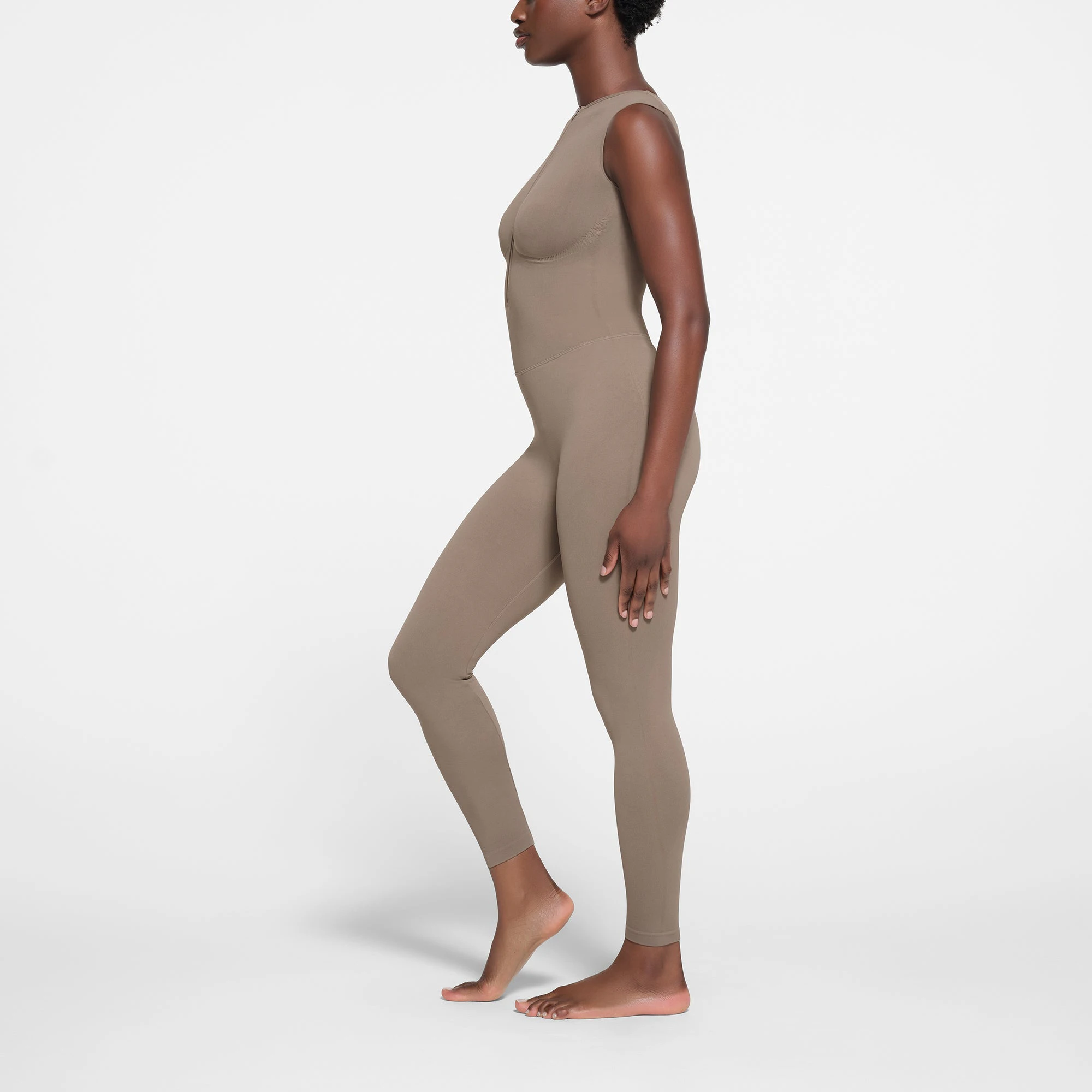 CONTOUR NYLON ZIP FRONT CATSUIT | TRUFFLE ON A MODEL SIDE VIEW