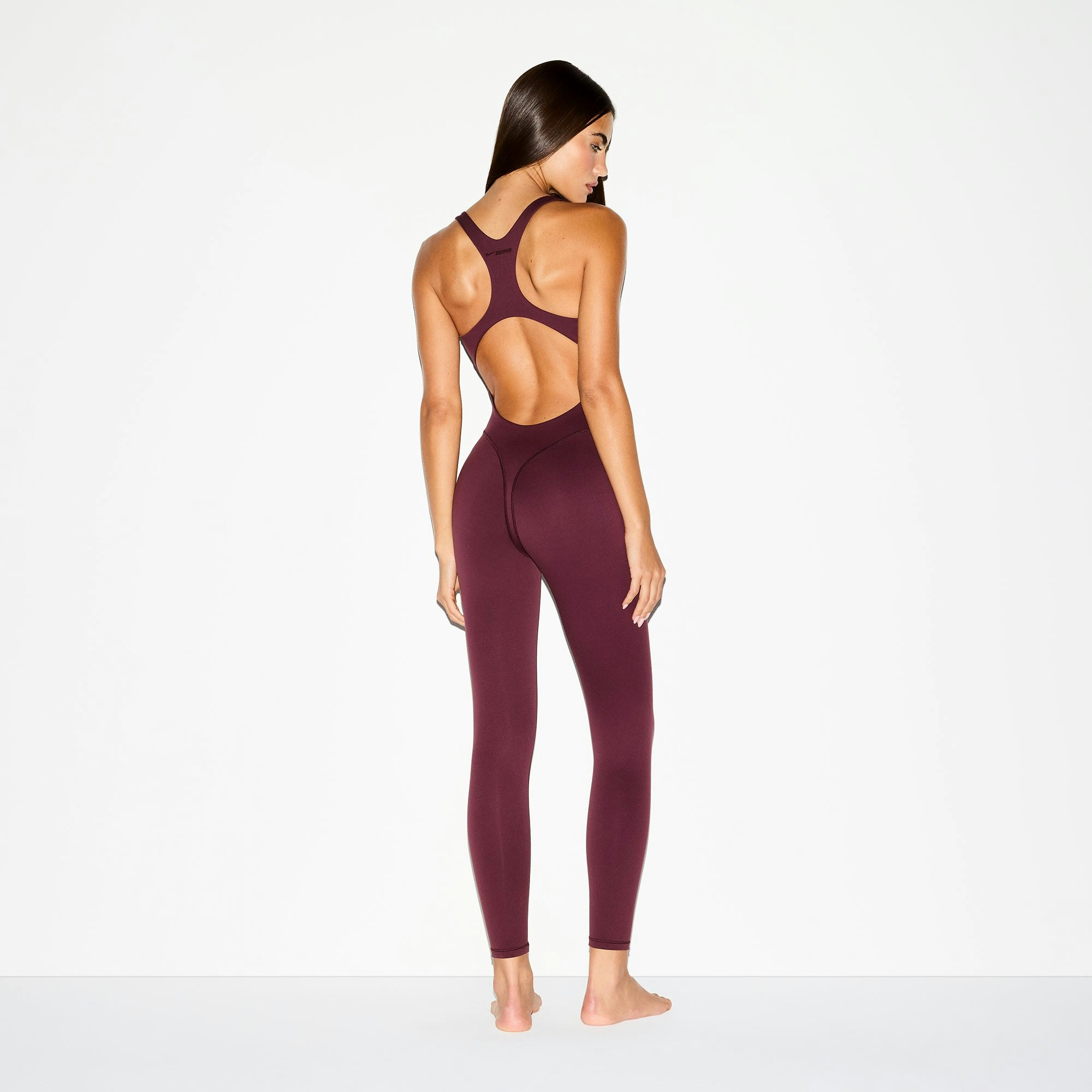 NikeSKIMS MATTE RACER LONG ONESIE | CURRANT ON A MODEL BACK VIEW @ | FOCUS: 0.0, 1.0, 0.9