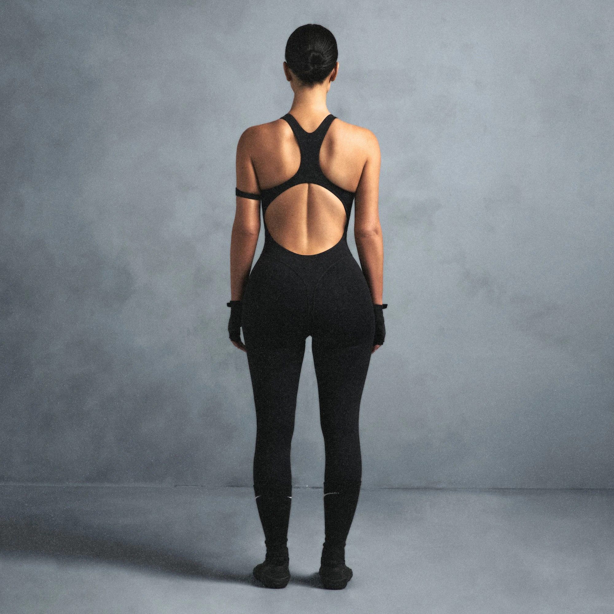 NikeSKIMS MATTE RACER LONG ONESIE | OBSIDIAN ON A MODEL SIDE VIEW @ | FOCUS: 0.0, 1.0, 0.9