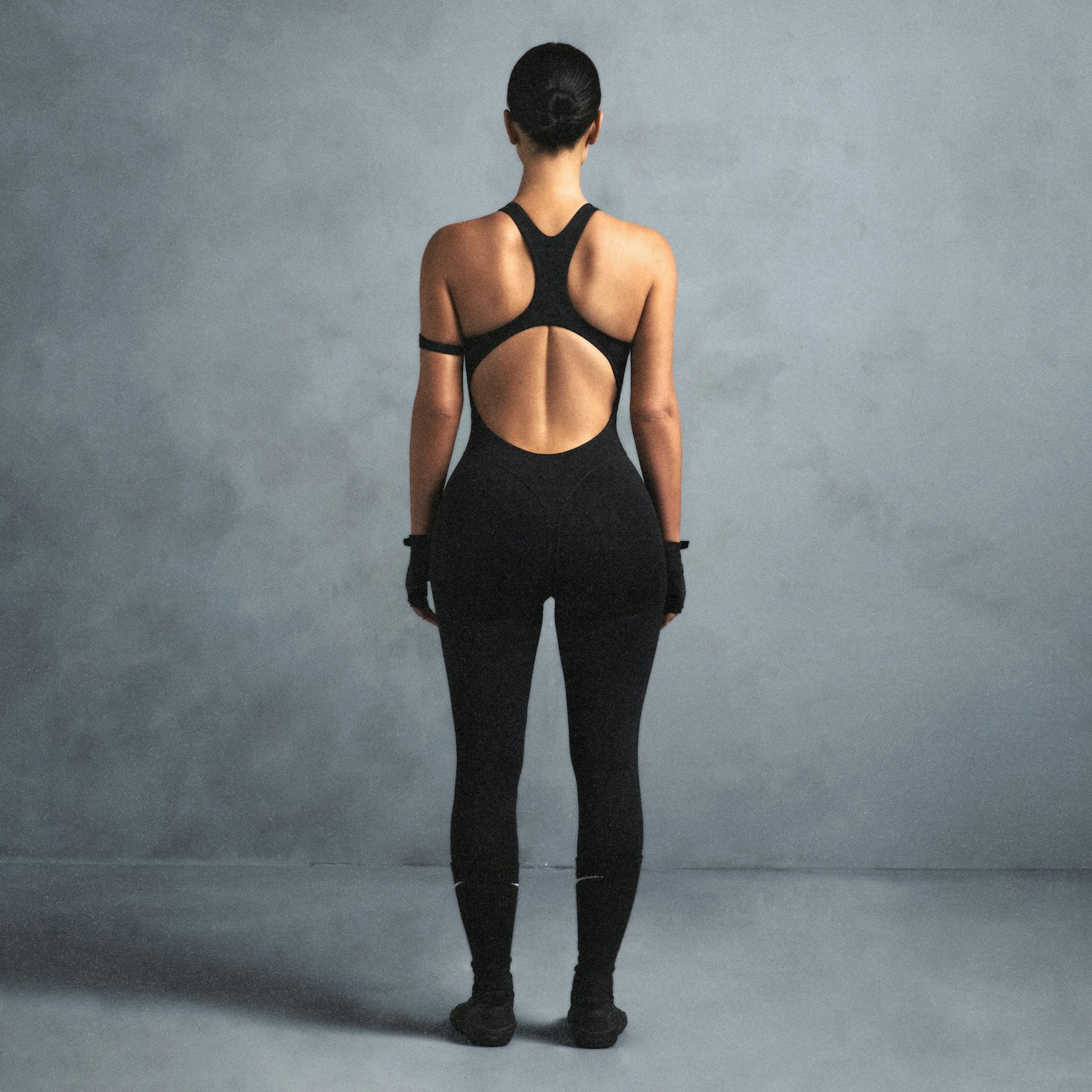 NikeSKIMS MATTE RACER LONG ONESIE | OBSIDIAN ON A MODEL SIDE VIEW @ | FOCUS: 0.0, 1.0, 0.9