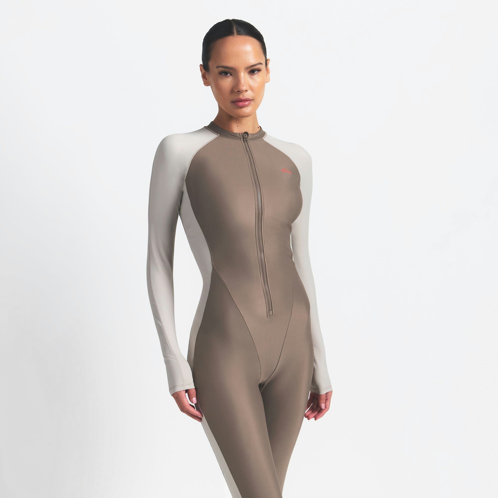 NikeSKIMS SHINE ZIP FRONT LONG ONESIE | TRUFFLE AND STONE ON A MODEL FRONT VIEW @ | FOCUS: 0.0, 1.0, 0.9