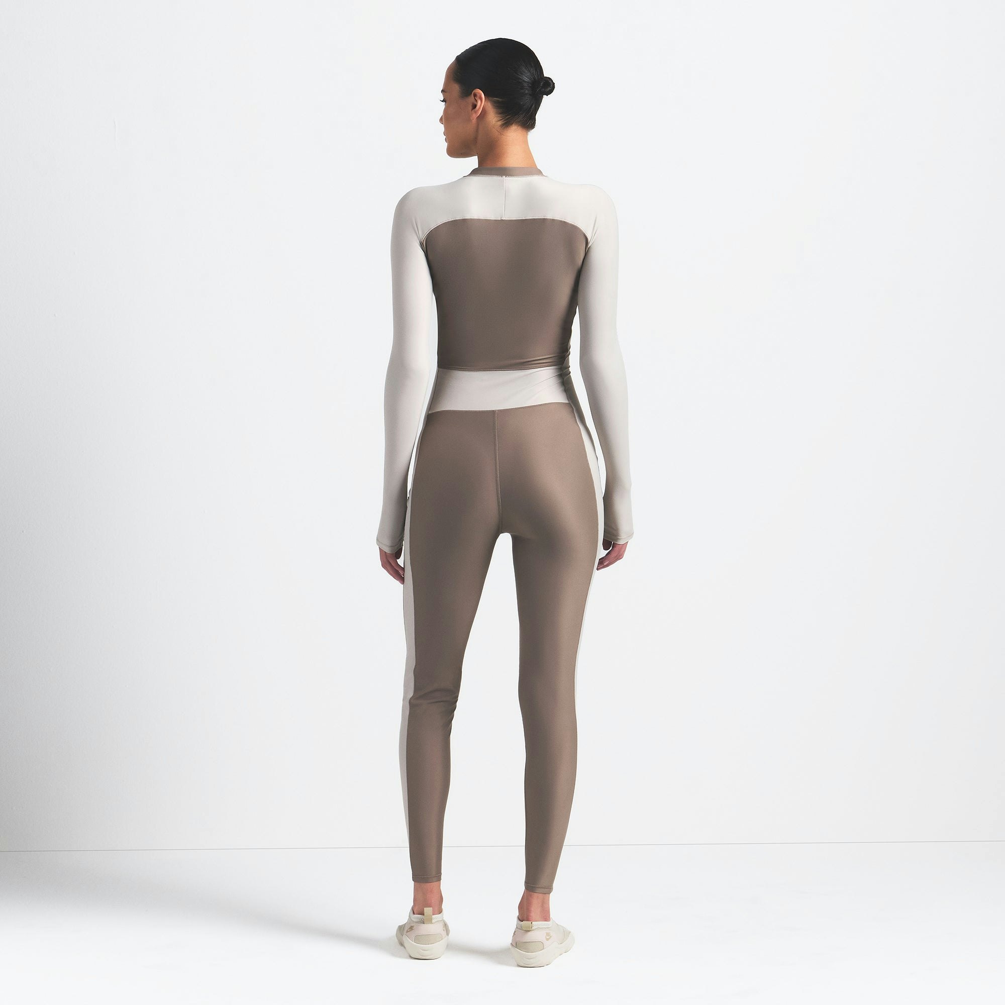 NikeSKIMS SHINE ZIP FRONT LONG ONESIE | TRUFFLE AND STONE ON A MODEL BACK VIEW @ | FOCUS: 0.0, 1.0, 0.9