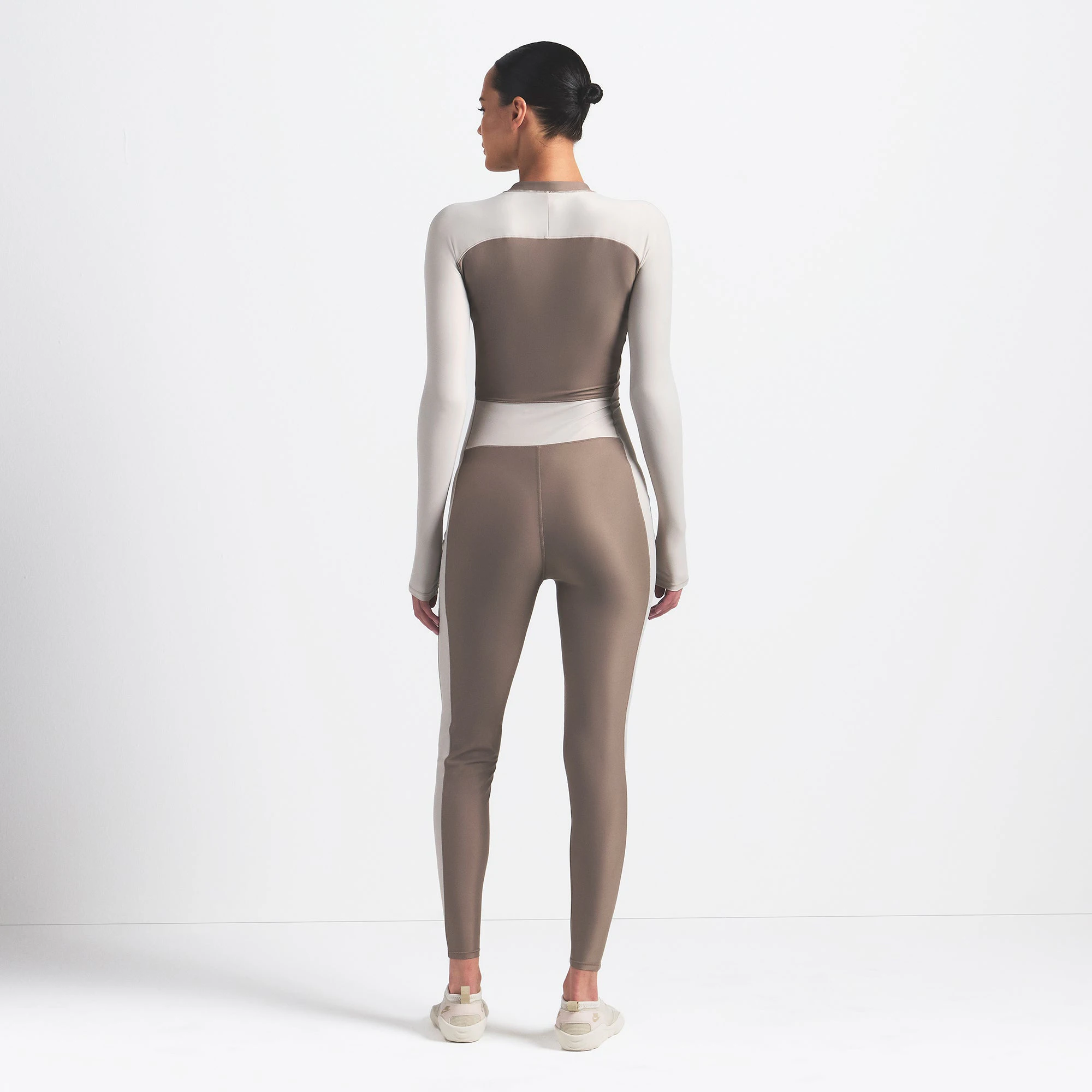 NikeSKIMS SHINE ZIP FRONT LONG ONESIE | TRUFFLE AND STONE ON A MODEL BACK VIEW @ | FOCUS: 0.0, 1.0, 0.9