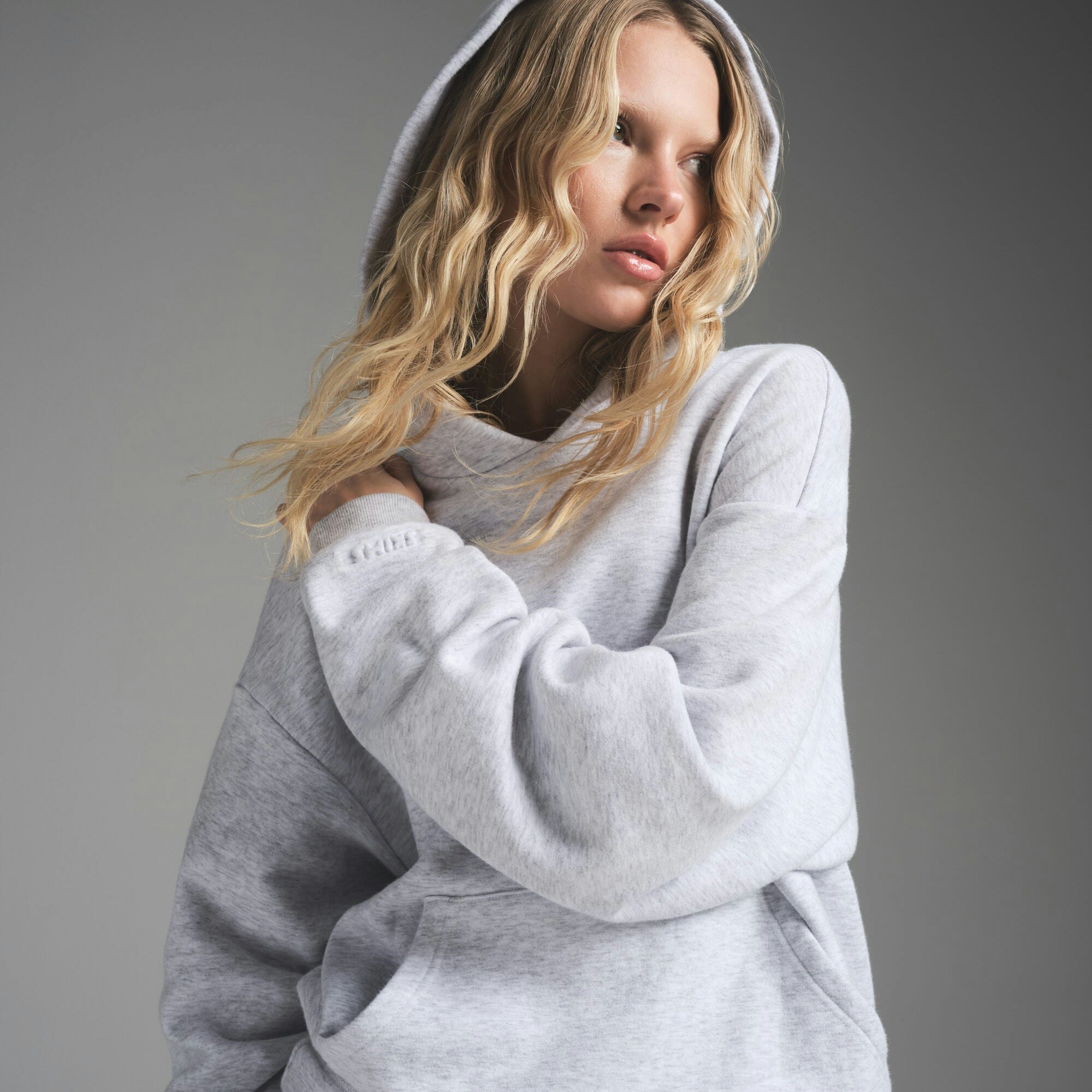 COTTON FLEECE CLASSIC HOODIE | LIGHT HEATHER GREY ON A MODEL FRONT VIEW | FOCUS: 0.0, 1.0, 0.9