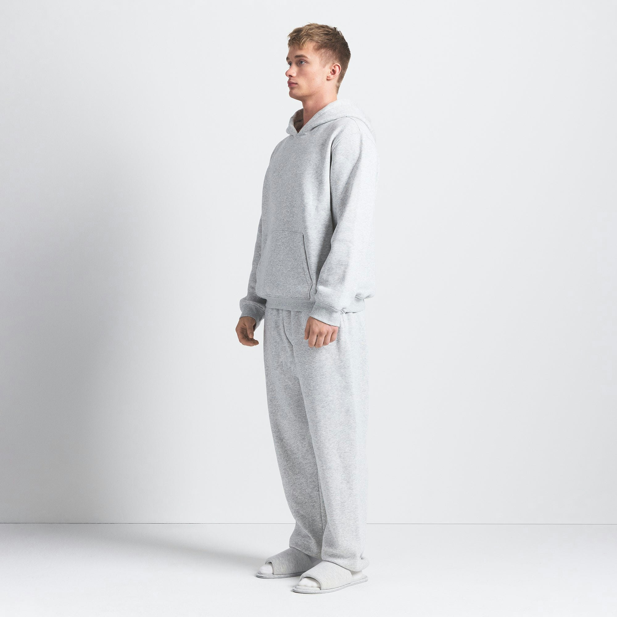 FLEECE LOUNGE MENS RELAXED HOODIE | LIGHT HEATHER GREY ON A MODEL SIDE VIEW @ | FOCUS: 0.0, 1.0, 0.9