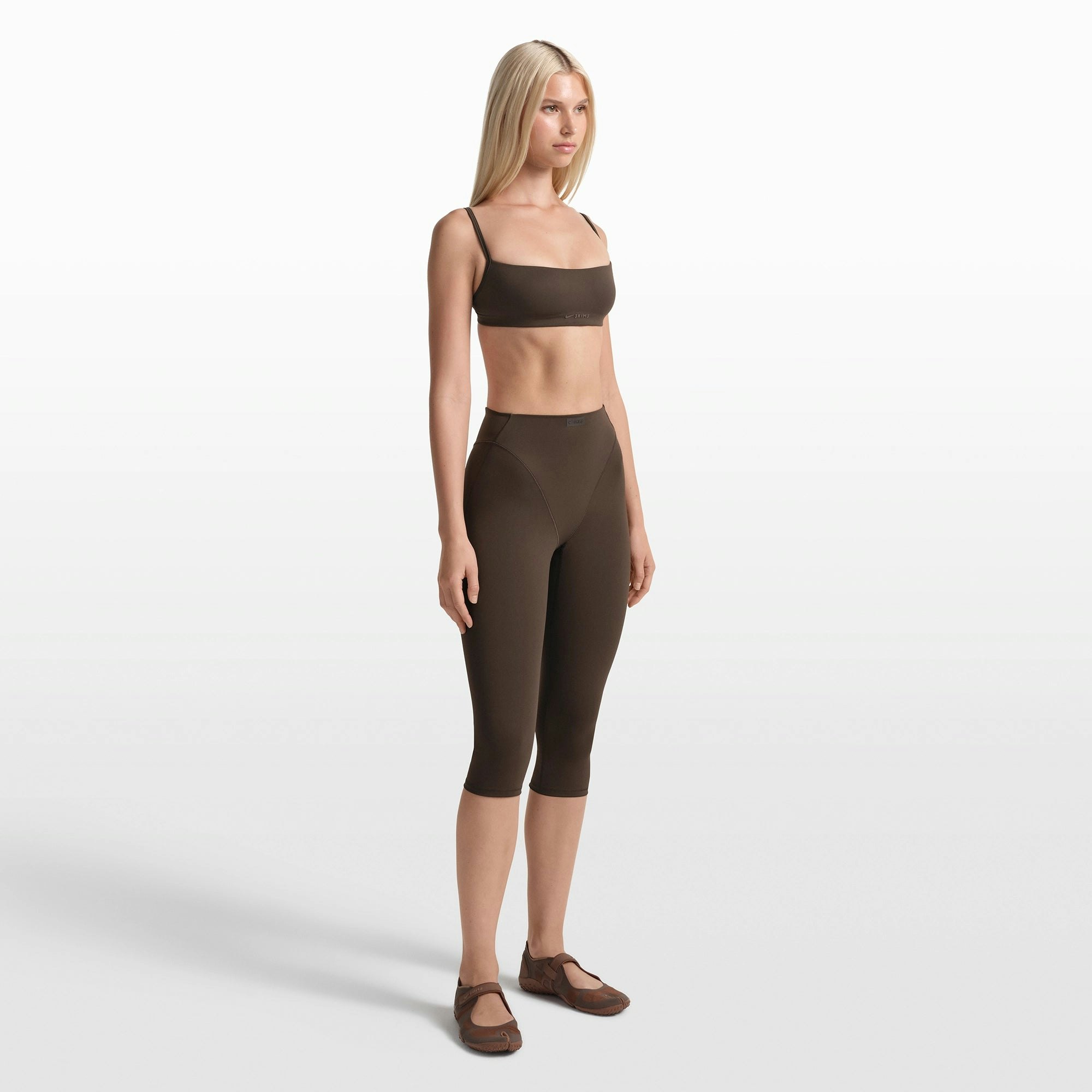 NikeSKIMS MATTE 17" V-LINE CROP LEGGING | DARK SEPIA ON A MODEL FRONT VIEW @ | FOCUS: 0.0, 1.0, 0.9