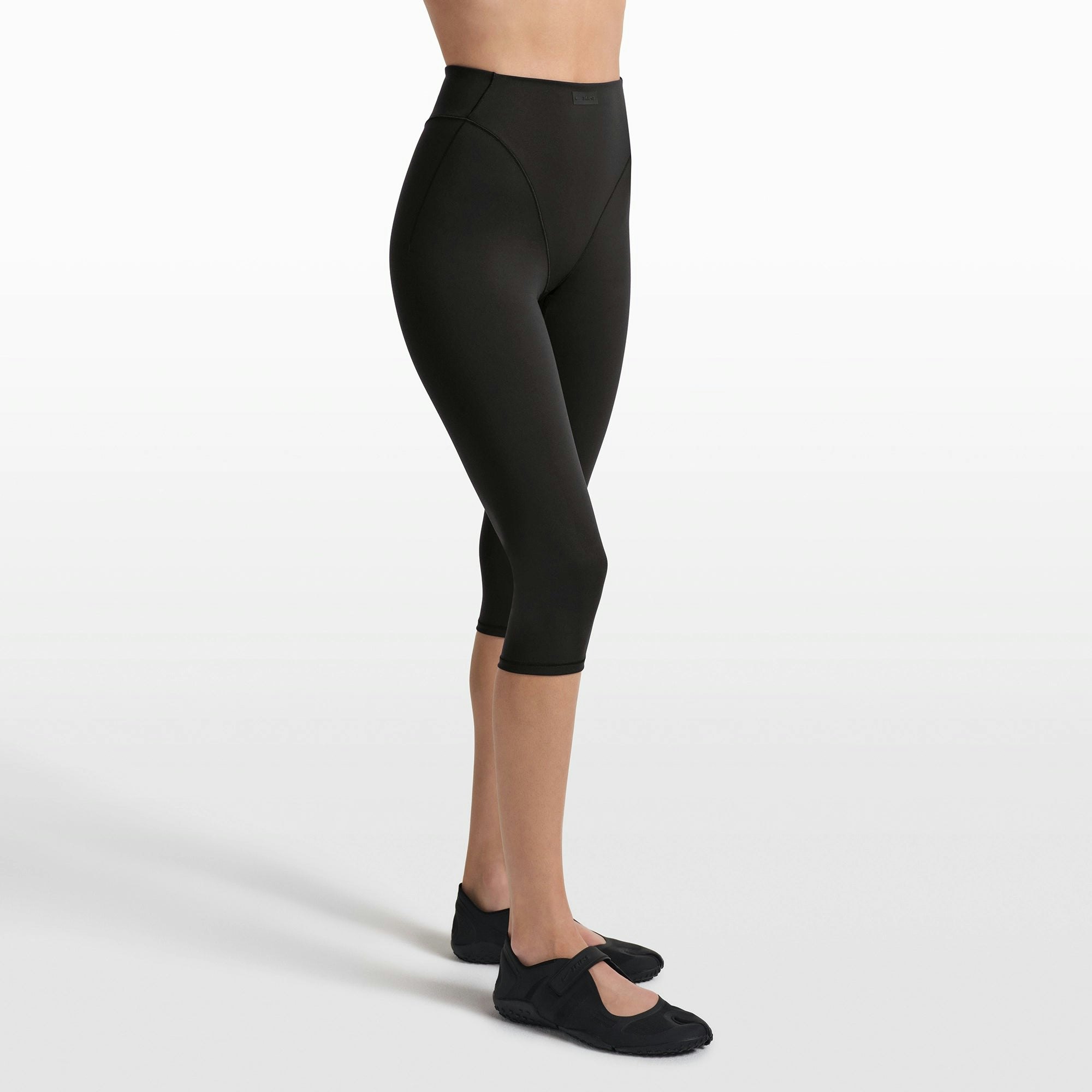 NikeSKIMS MATTE 17" V-LINE CROP LEGGING | OBSIDIAN ON A MODEL FRONT VIEW @ | FOCUS: 0.0, 1.0, 0.9