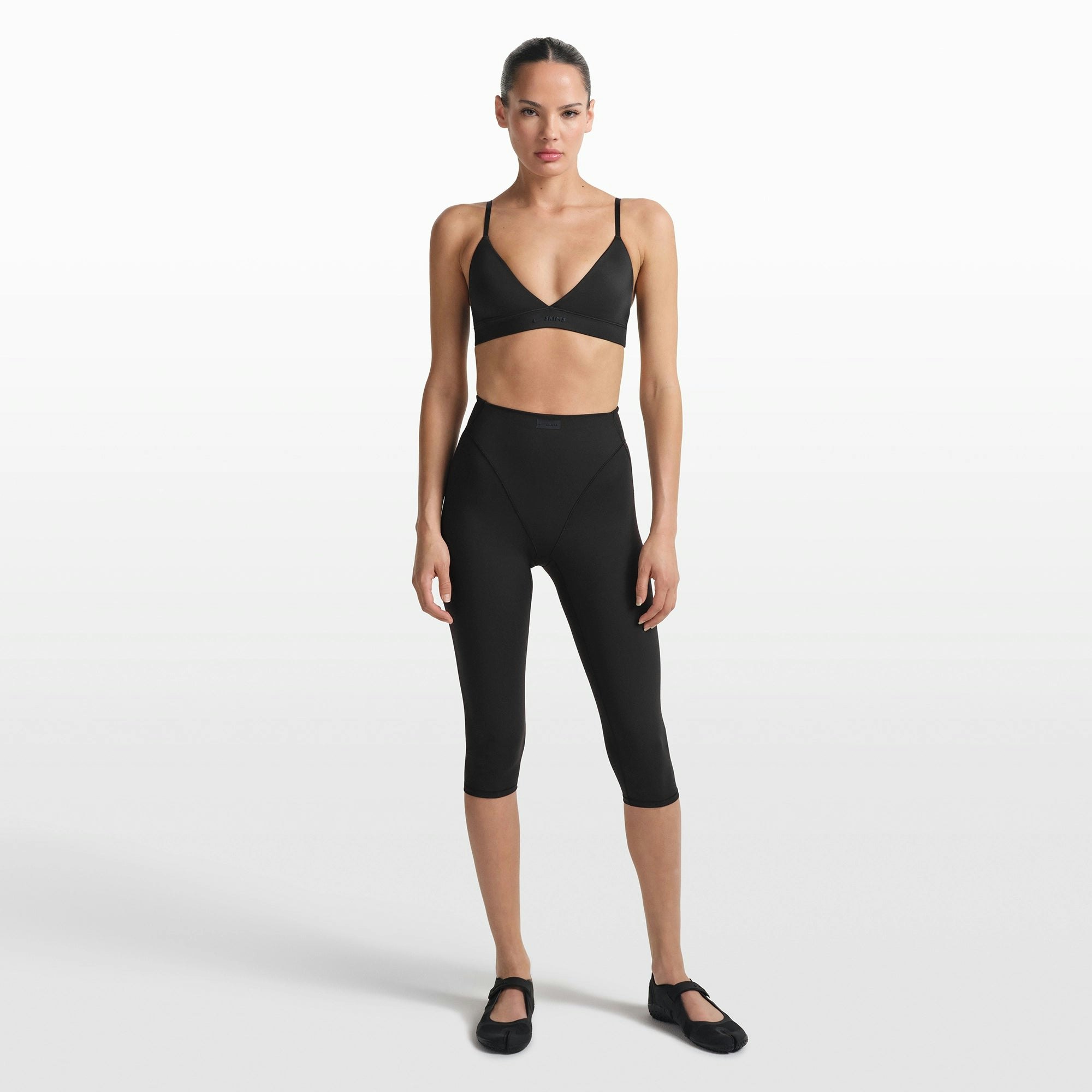 NikeSKIMS MATTE 17" V-LINE CROP LEGGING | OBSIDIAN ON A MODEL FRONT VIEW @ | FOCUS: 0.0, 1.0, 0.9