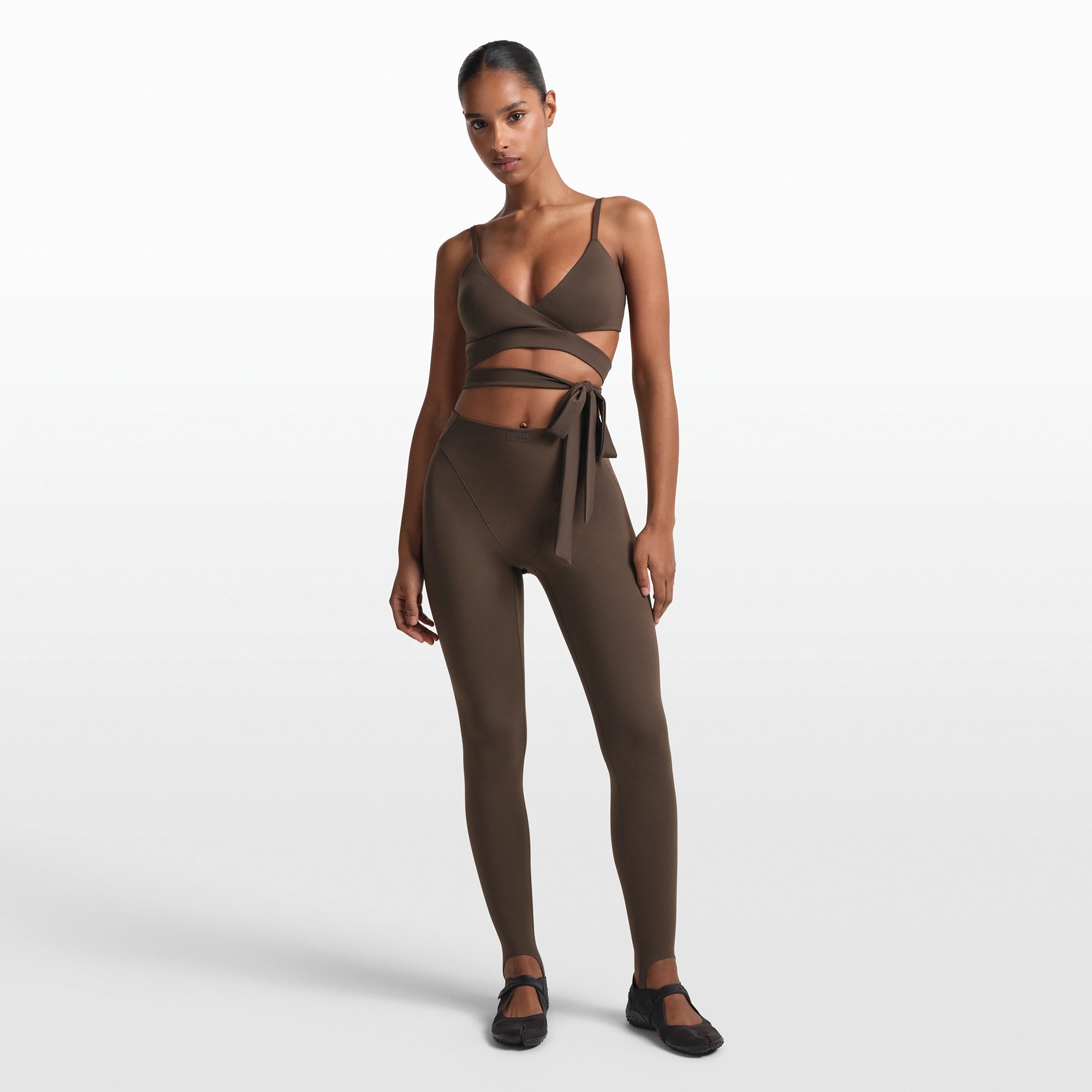 NikeSKIMS MATTE V-LINE STIRRUP LEGGING | DARK SEPIA ON A MODEL FRONT VIEW @ | FOCUS: 0.0, 1.0, 0.9