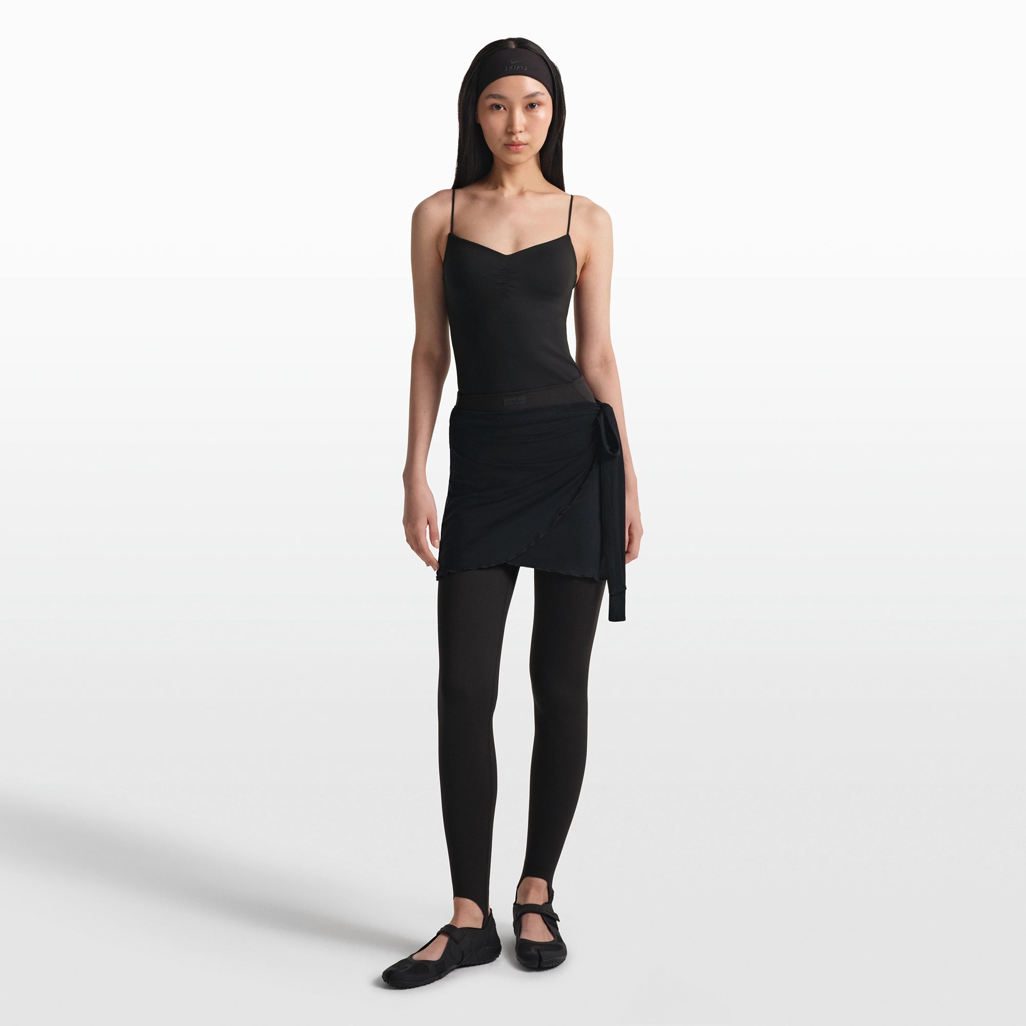 NikeSKIMS MATTE V-LINE STIRRUP LEGGING | OBSIDIAN ON A MODEL FRONT VIEW @ | FOCUS: 0.0, 1.0, 0.9
