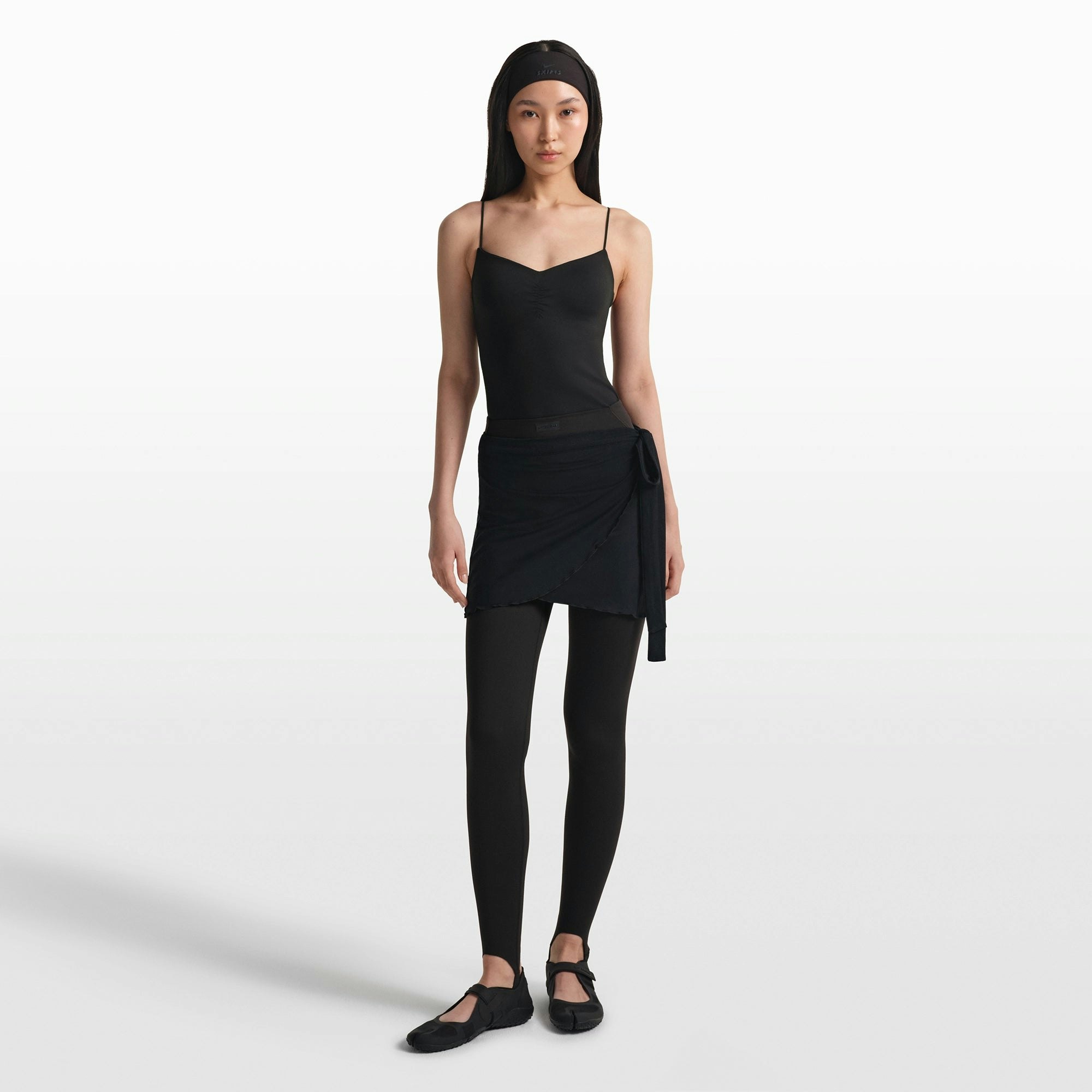 NikeSKIMS MATTE V-LINE STIRRUP LEGGING | OBSIDIAN ON A MODEL FRONT VIEW @ | FOCUS: 0.0, 1.0, 0.9