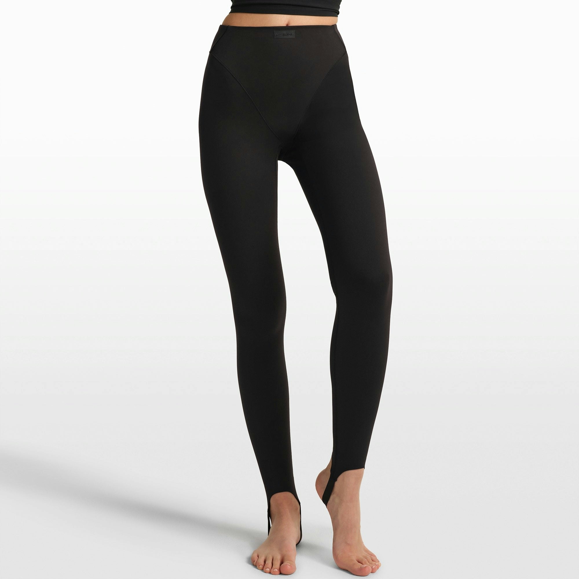 NikeSKIMS MATTE V-LINE STIRRUP LEGGING | OBSIDIAN ON A MODEL FRONT VIEW @ | FOCUS: 0.0, 1.0, 0.9