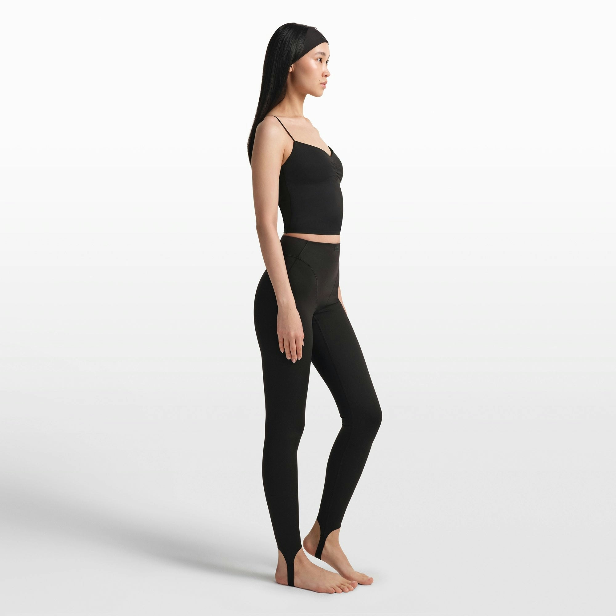 NikeSKIMS MATTE V-LINE STIRRUP LEGGING | OBSIDIAN ON A MODEL FRONT VIEW @ | FOCUS: 0.0, 1.0, 0.9