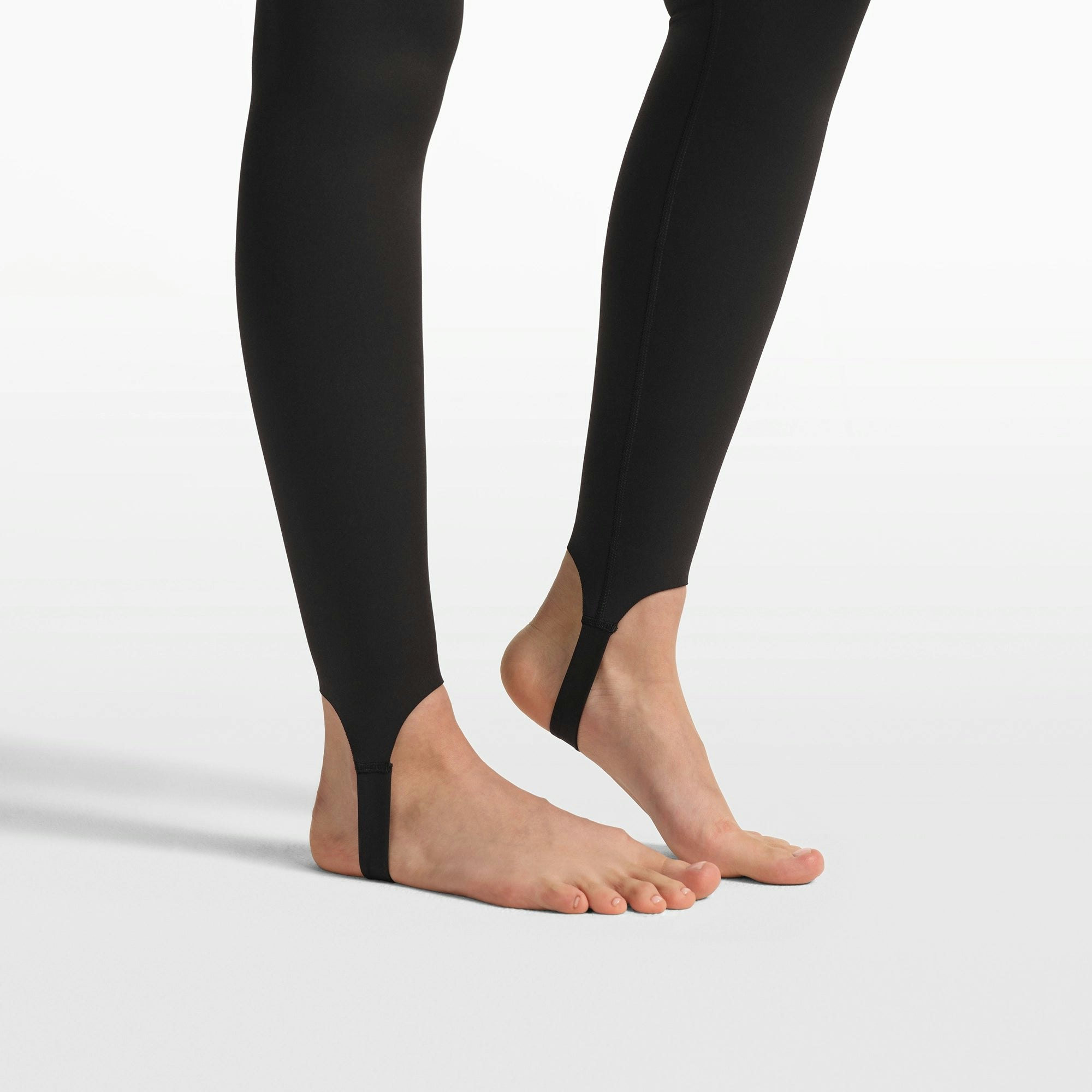 NikeSKIMS MATTE V-LINE STIRRUP LEGGING | OBSIDIAN ON A MODEL FRONT VIEW @ | FOCUS: 0.0, 1.0, 0.9