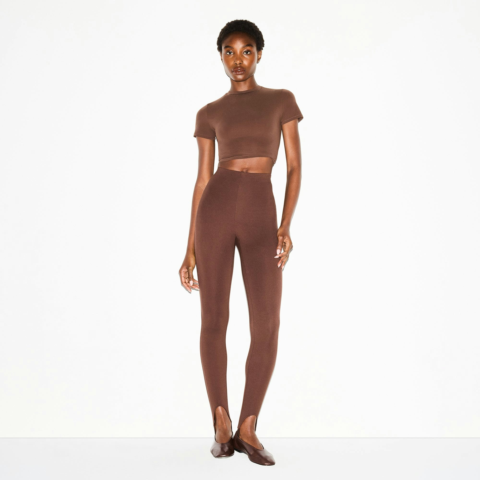 THE ESSENTIAL COLLECTION HIGH-WAISTED STIRRUP LEGGING | COCOA ON A MODEL FRONT VIEW @ | FOCUS: 0.0, 1.0, 0.9