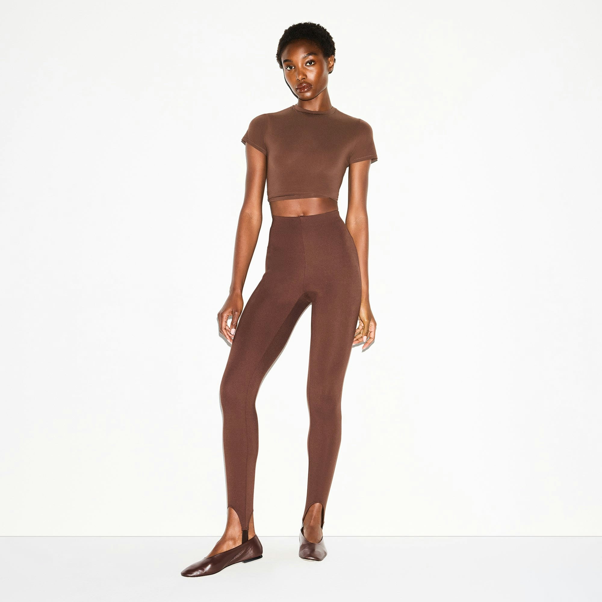 THE ESSENTIAL COLLECTION HIGH-WAISTED STIRRUP LEGGING | COCOA ON A MODEL FRONT VIEW @ | FOCUS: 0.0, 1.0, 0.9