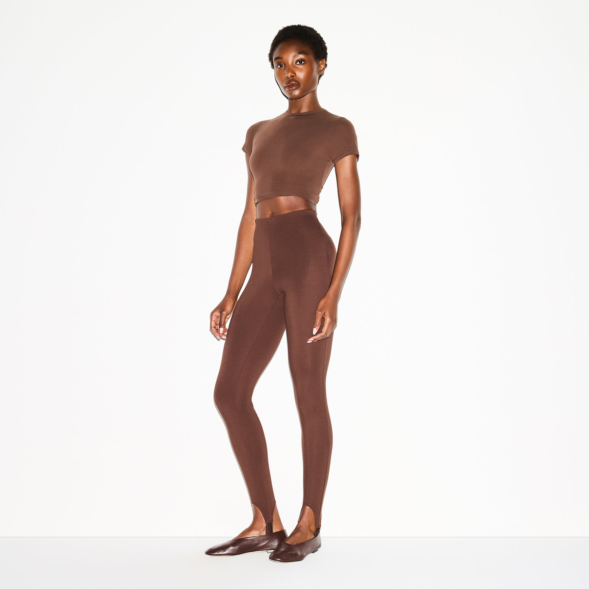THE ESSENTIAL COLLECTION HIGH-WAISTED STIRRUP LEGGING | COCOA ON A MODEL SIDE VIEW @ | FOCUS: 0.0, 1.0, 0.9