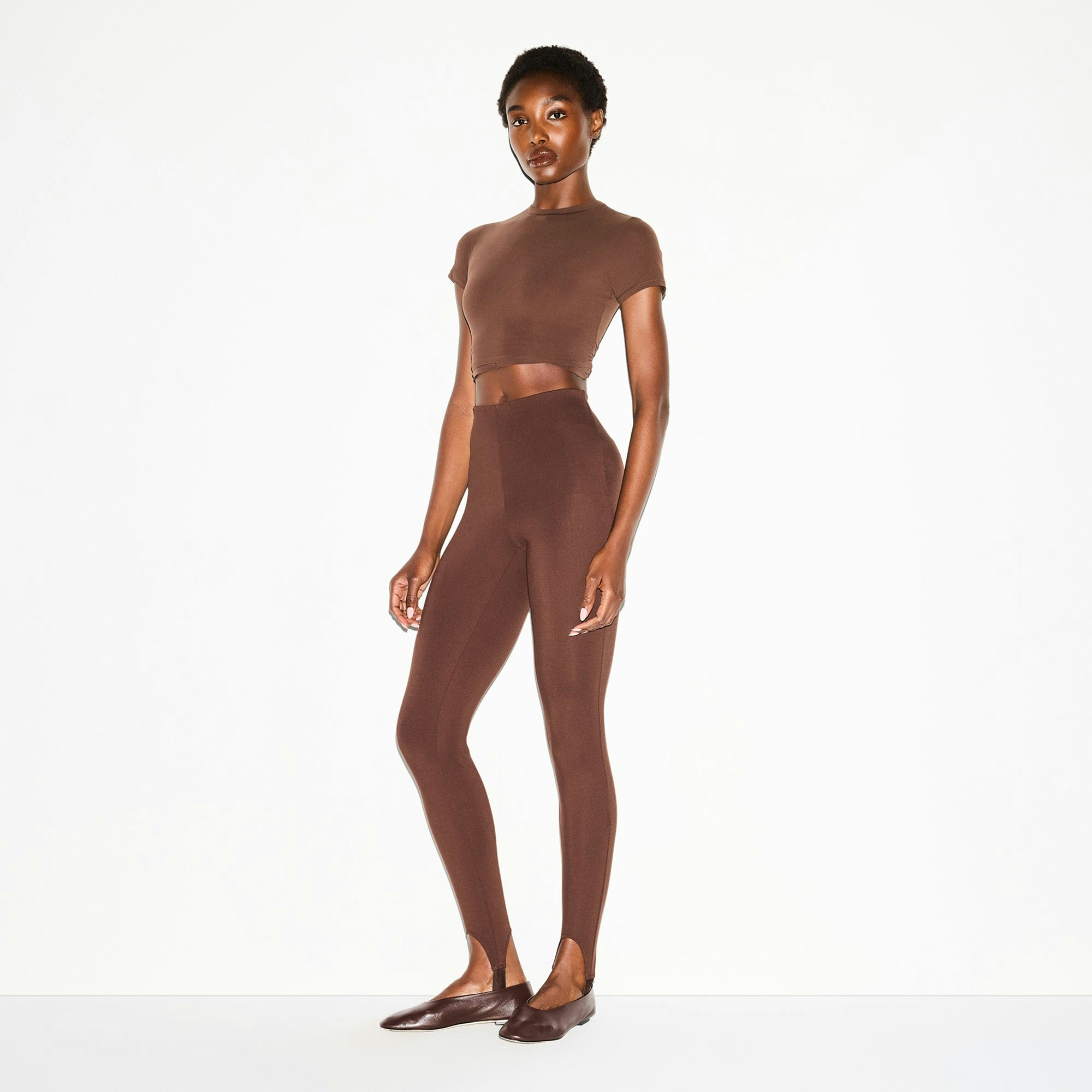 THE ESSENTIAL COLLECTION HIGH-WAISTED STIRRUP LEGGING | COCOA ON A MODEL SIDE VIEW @ | FOCUS: 0.0, 1.0, 0.9