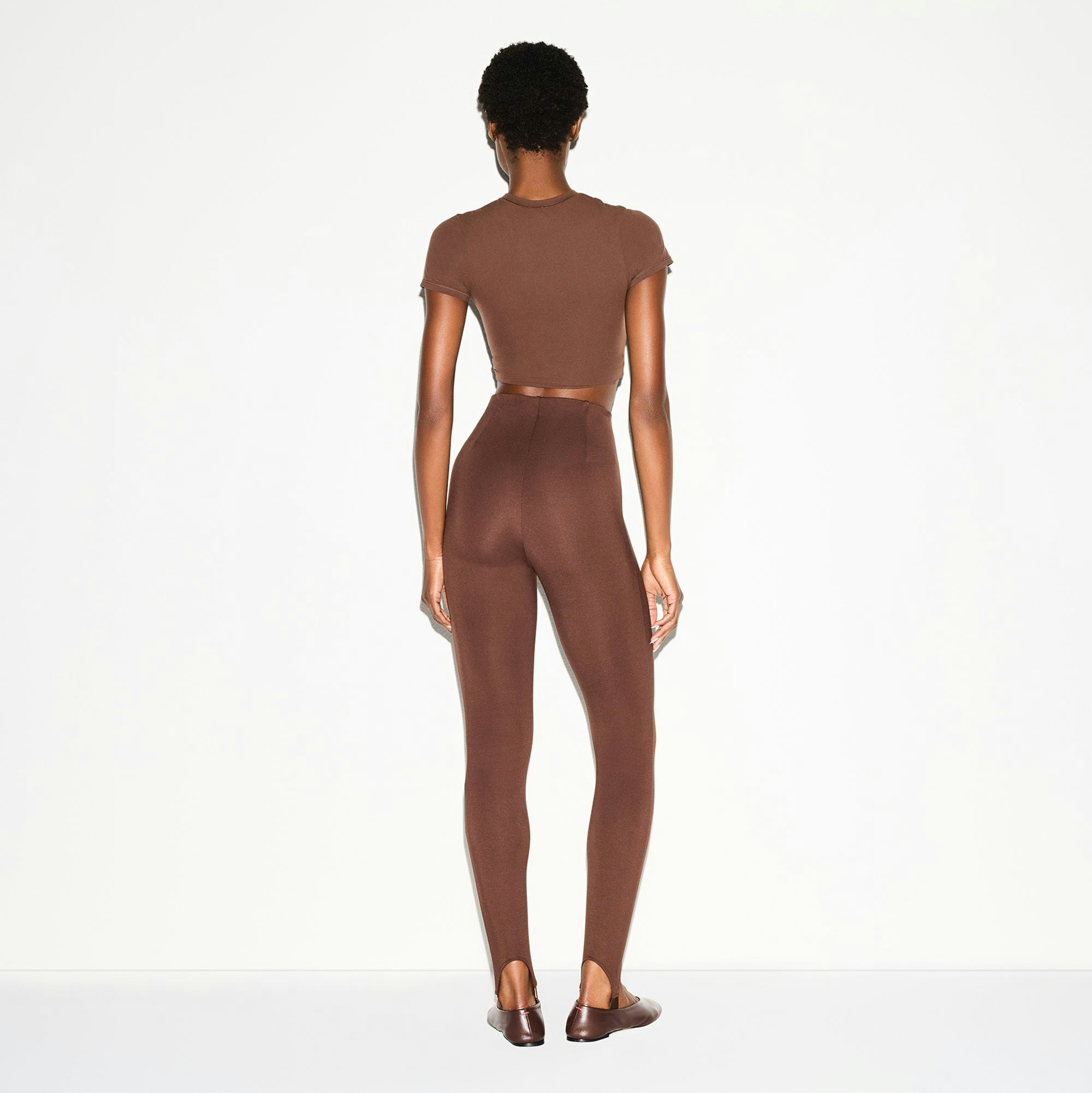 THE ESSENTIAL COLLECTION HIGH-WAISTED STIRRUP LEGGING | COCOA ON A MODEL BACK VIEW @ | FOCUS: 0.0, 1.0, 0.9