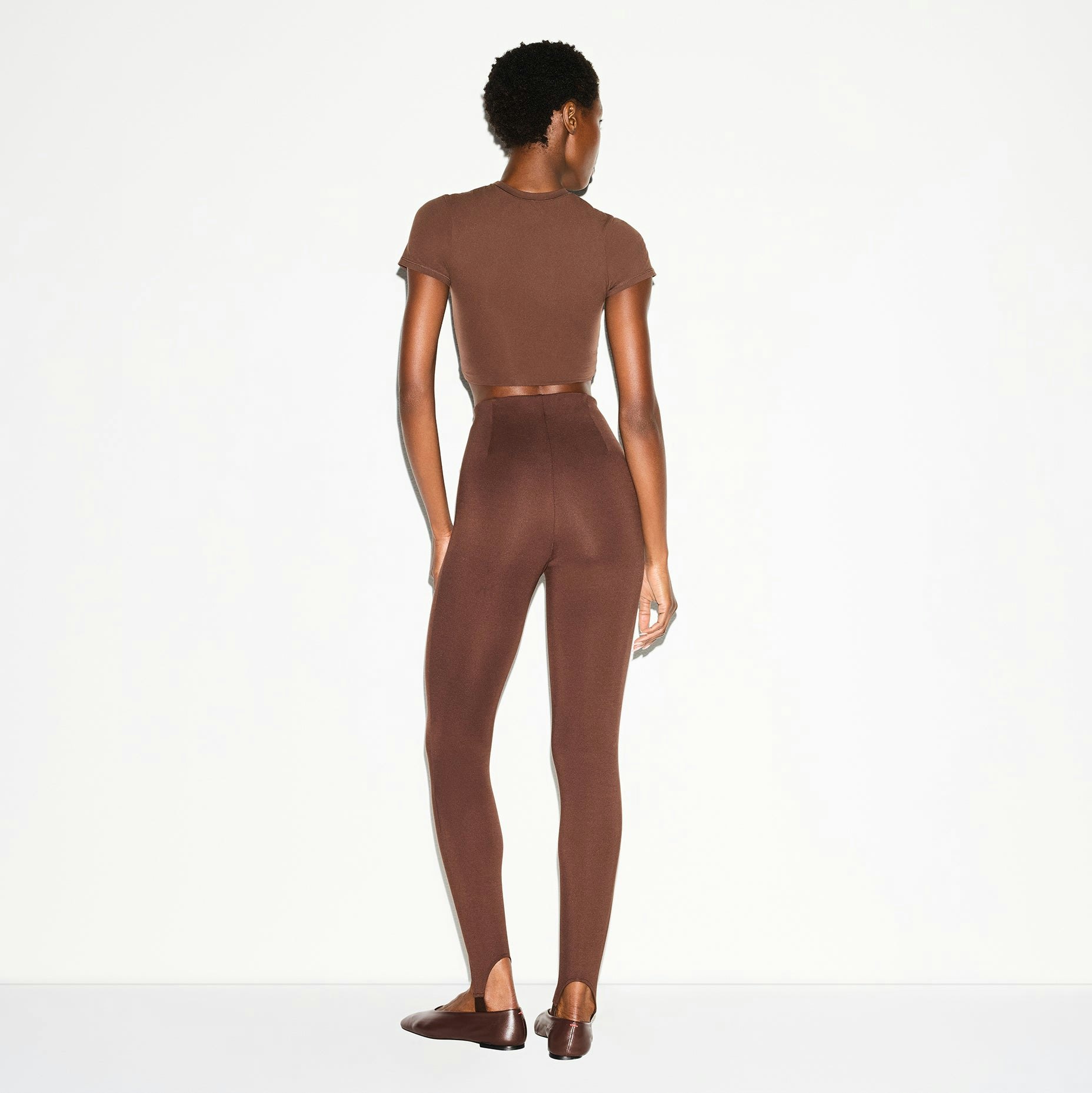 THE ESSENTIAL COLLECTION HIGH-WAISTED STIRRUP LEGGING | COCOA ON A MODEL BACK VIEW @ | FOCUS: 0.0, 1.0, 0.9