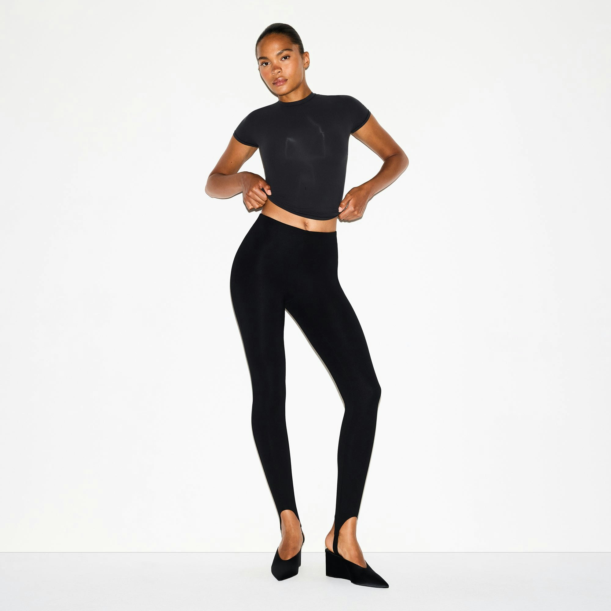 THE ESSENTIAL COLLECTION HIGH-WAISTED STIRRUP LEGGING | OBSIDIAN ON A MODEL FRONT VIEW @ | FOCUS: 0.0, 1.0, 0.9