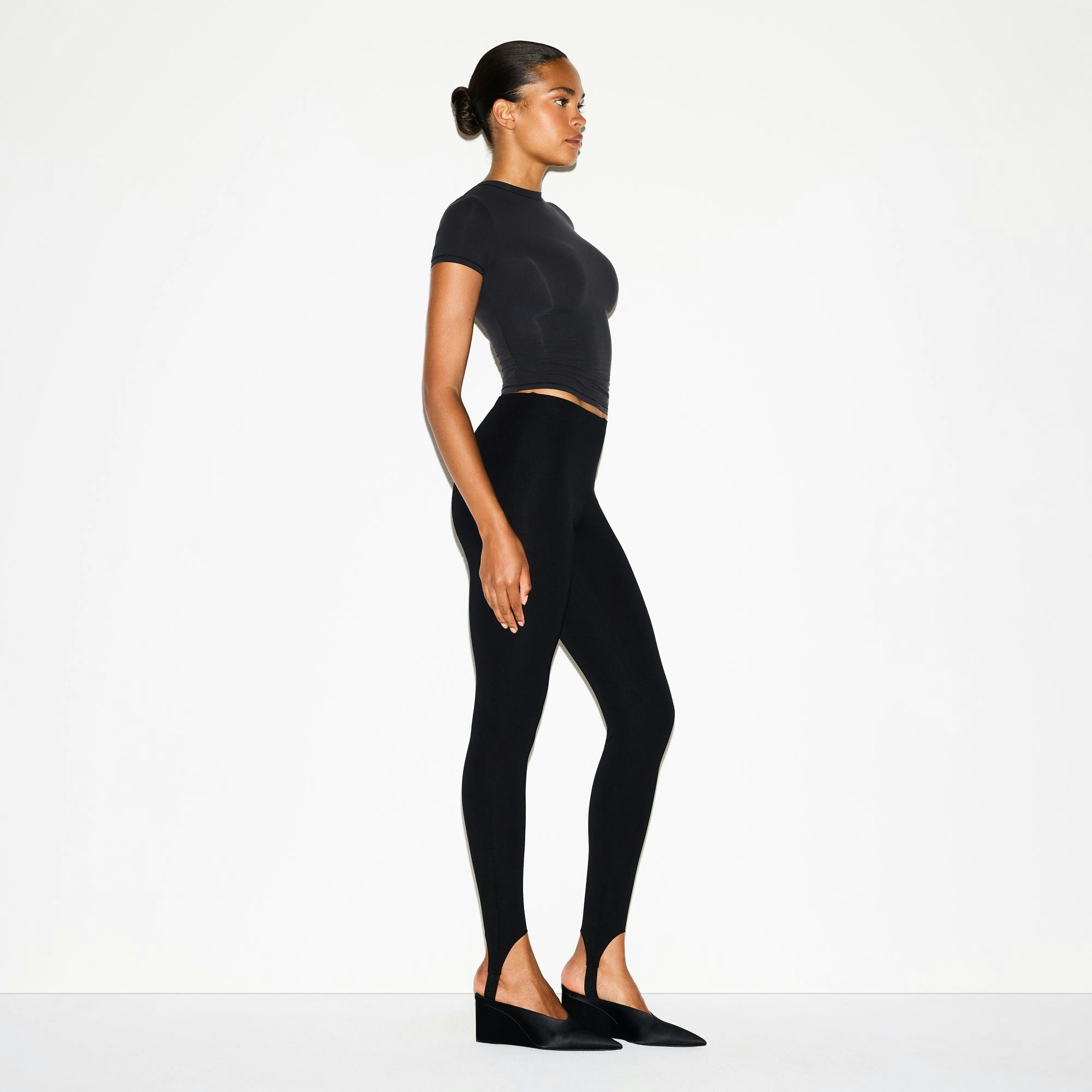 THE ESSENTIAL COLLECTION HIGH-WAISTED STIRRUP LEGGING | OBSIDIAN ON A MODEL FRONT VIEW @ | FOCUS: 0.0, 1.0, 0.9